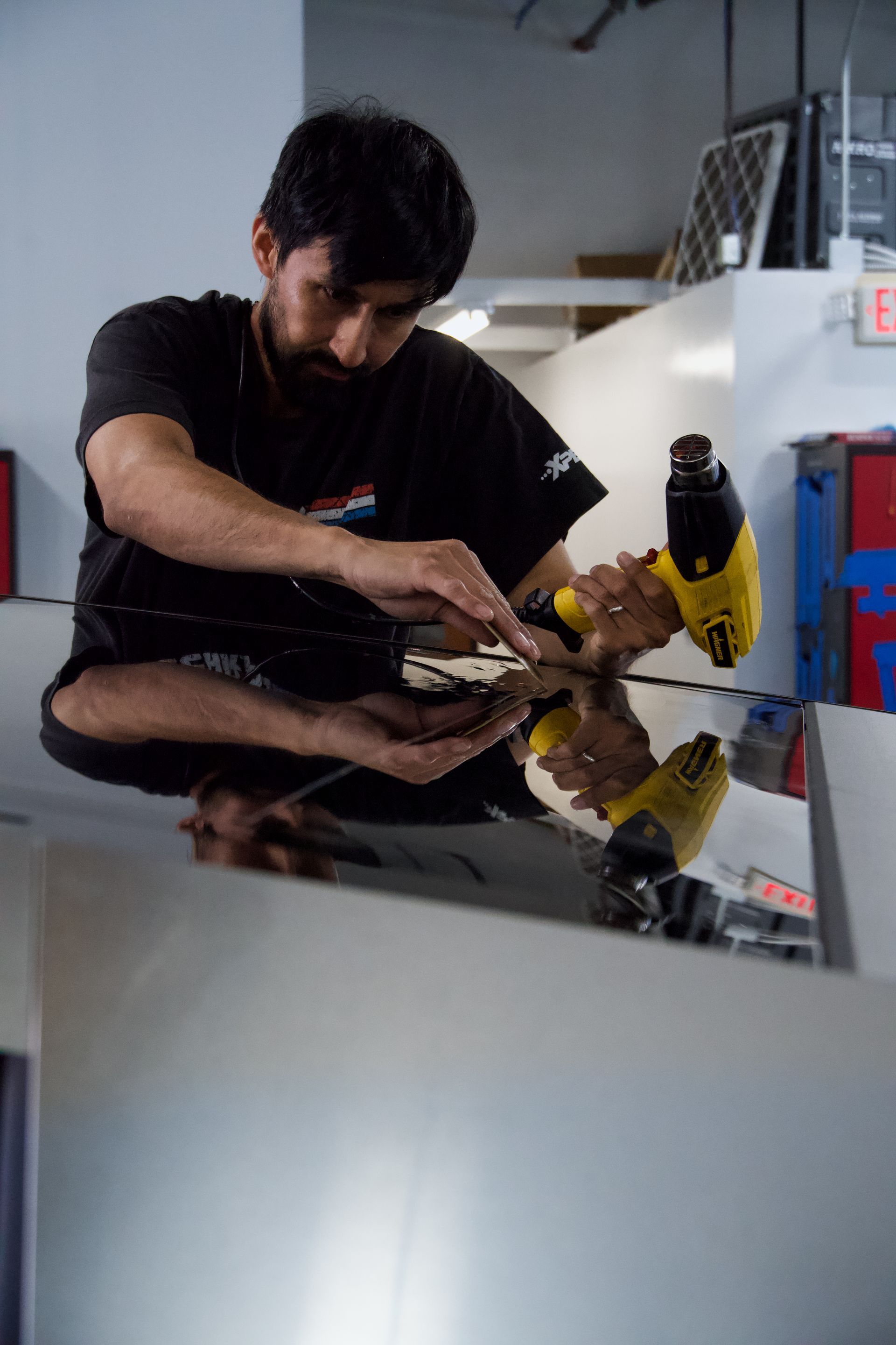 Man applying tint film with a heat gun in a garage.