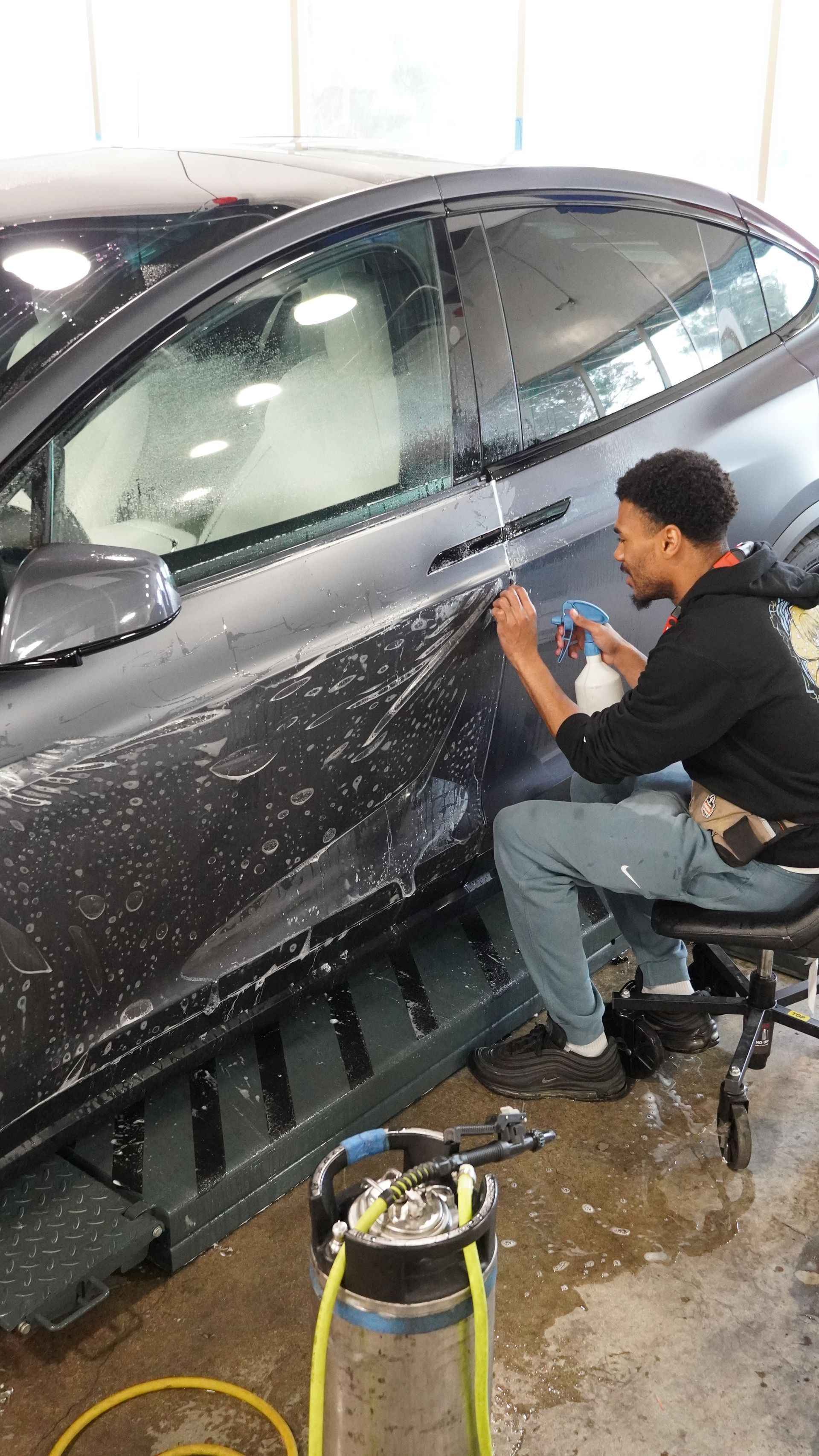 A man is sitting on a chair working on a car.