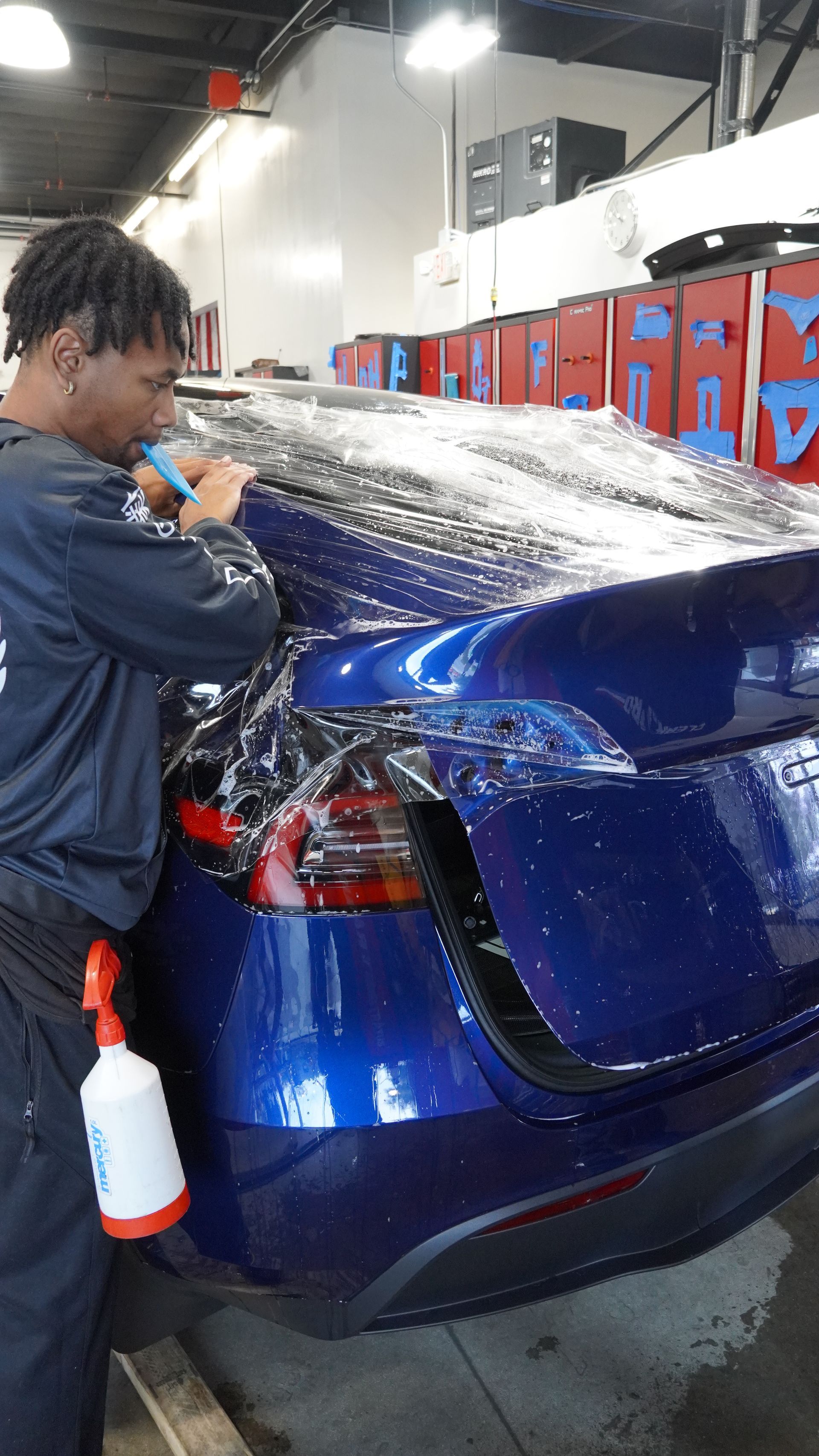A man is washing a blue car in a car wash.