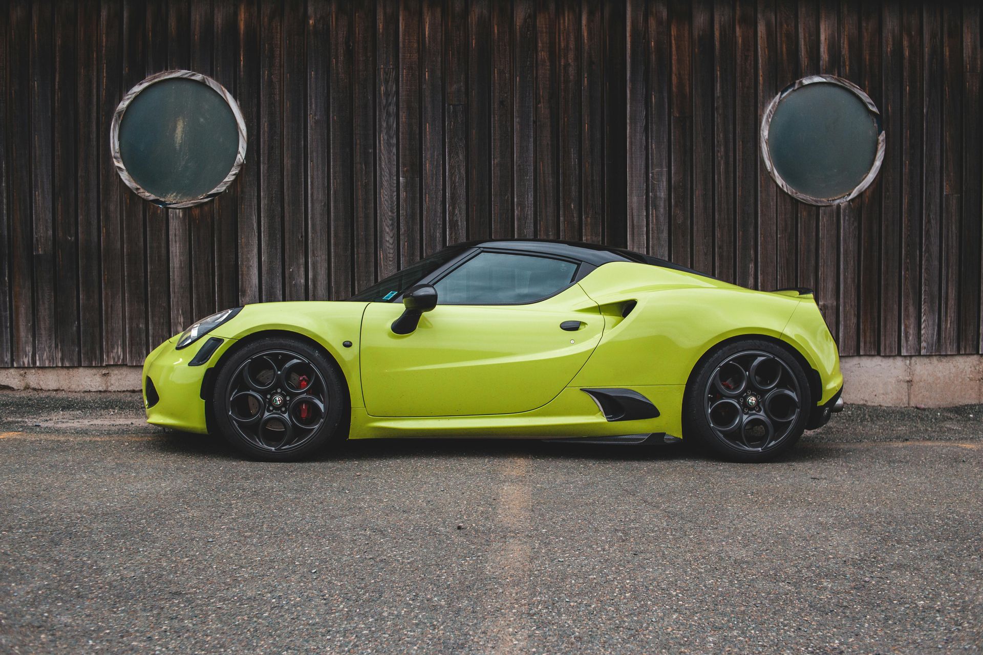 A yellow sports car is parked in front of a wooden building.