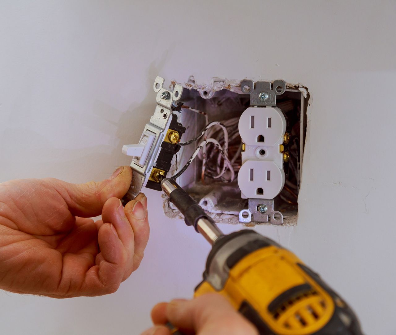 A person is installing an electrical outlet in a wall.