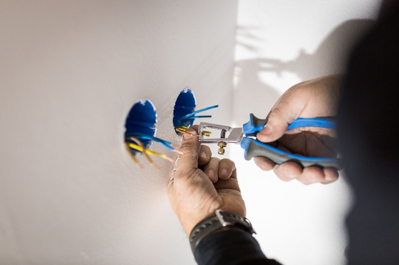 A person is holding a pair of pliers and cutting a wire.