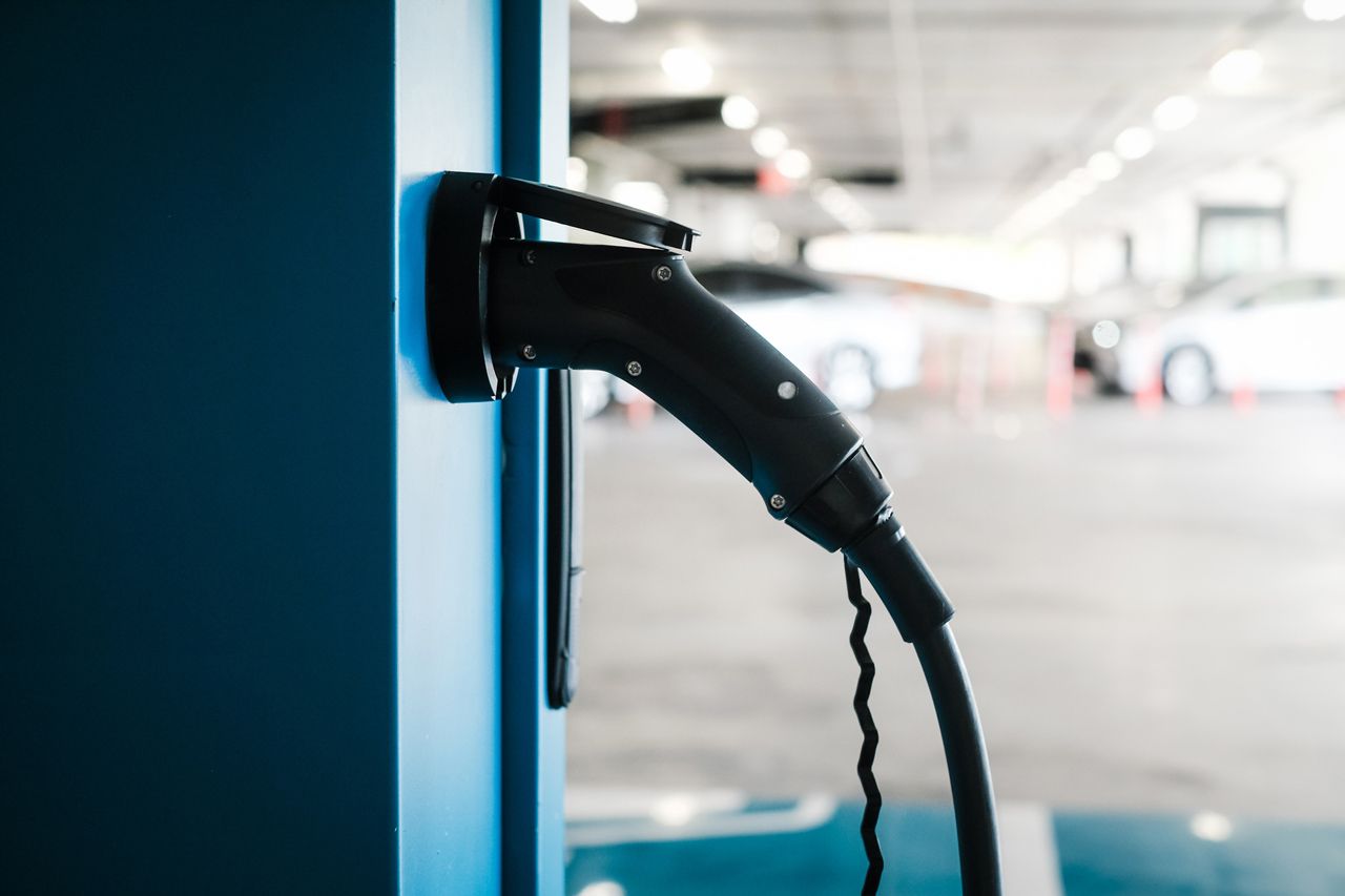 An electric car is being charged at a charging station in a parking garage.
