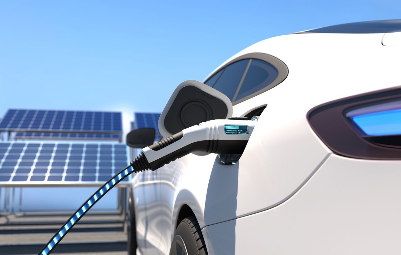 A white electric car is being charged by solar panels.
