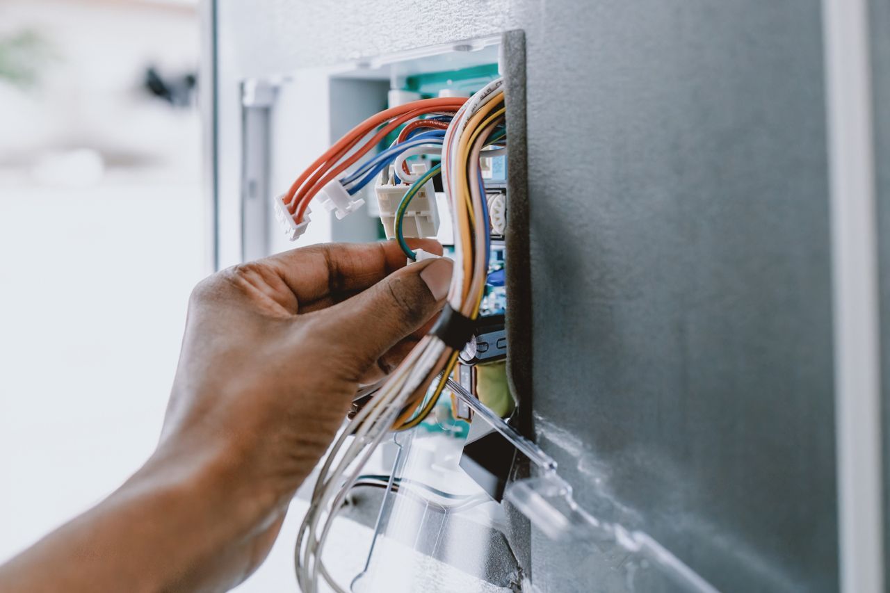 A person is fixing a refrigerator with wires.