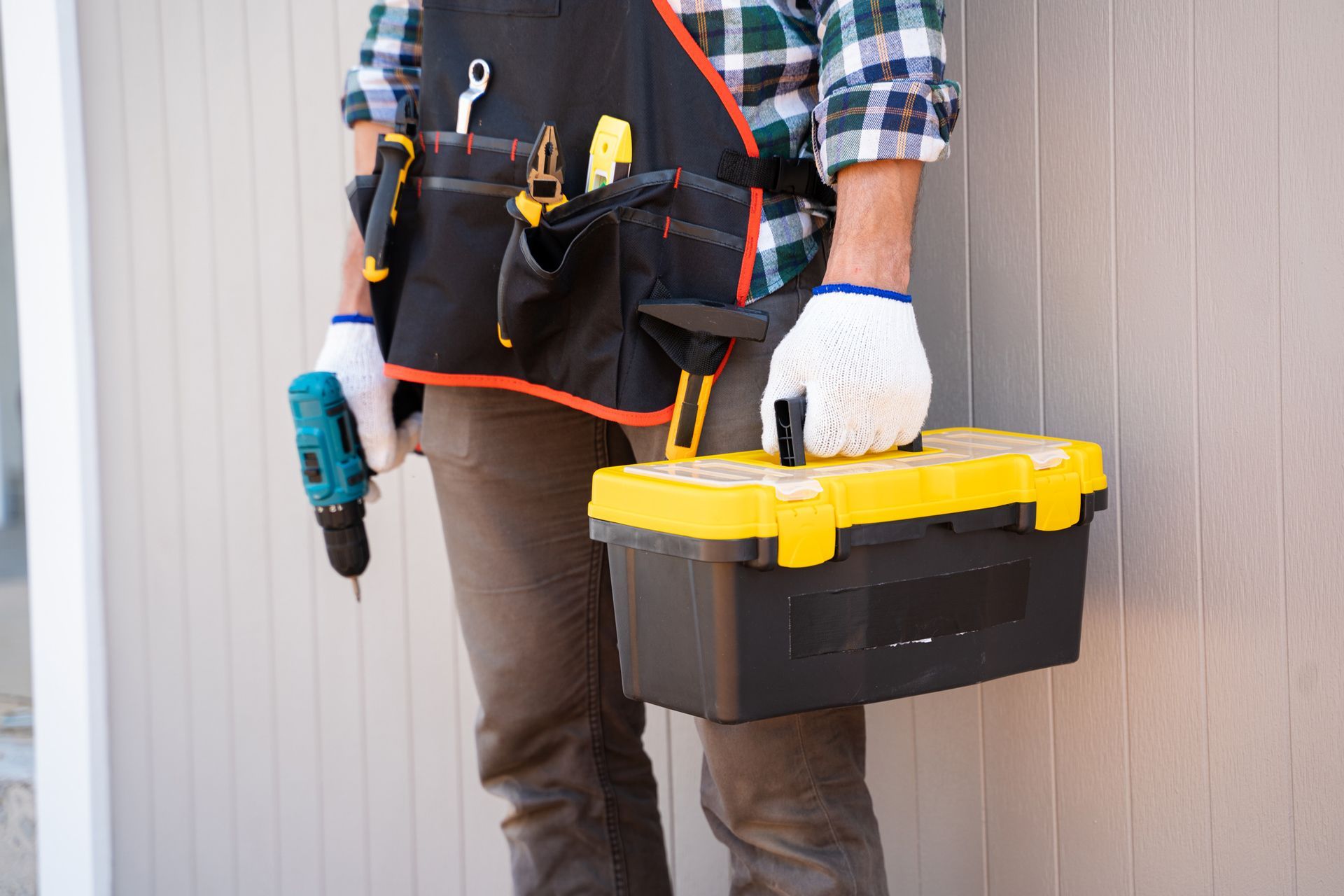 A man is holding a toolbox and a drill.