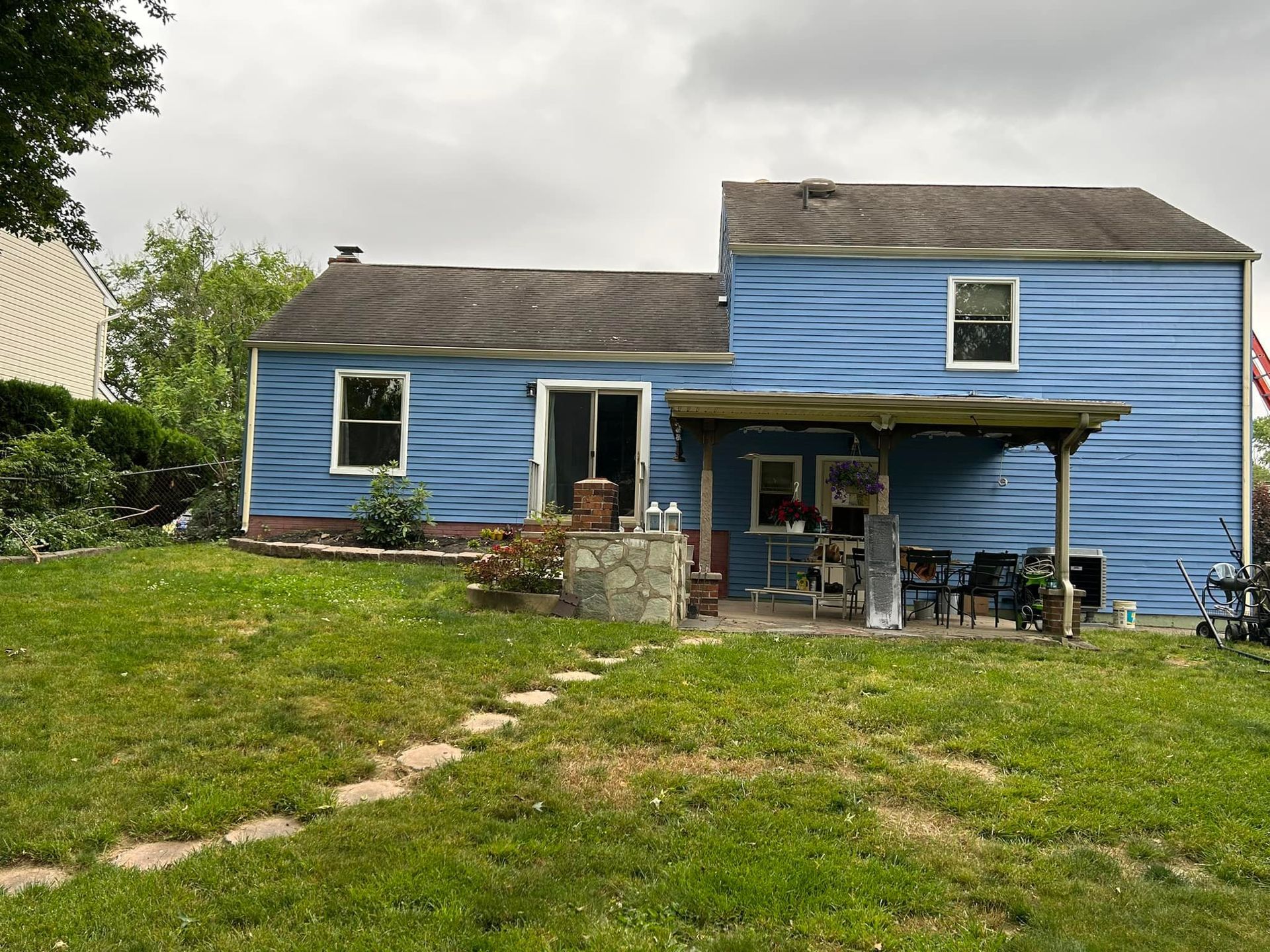 The back of a blue house with a large lawn in front of it.