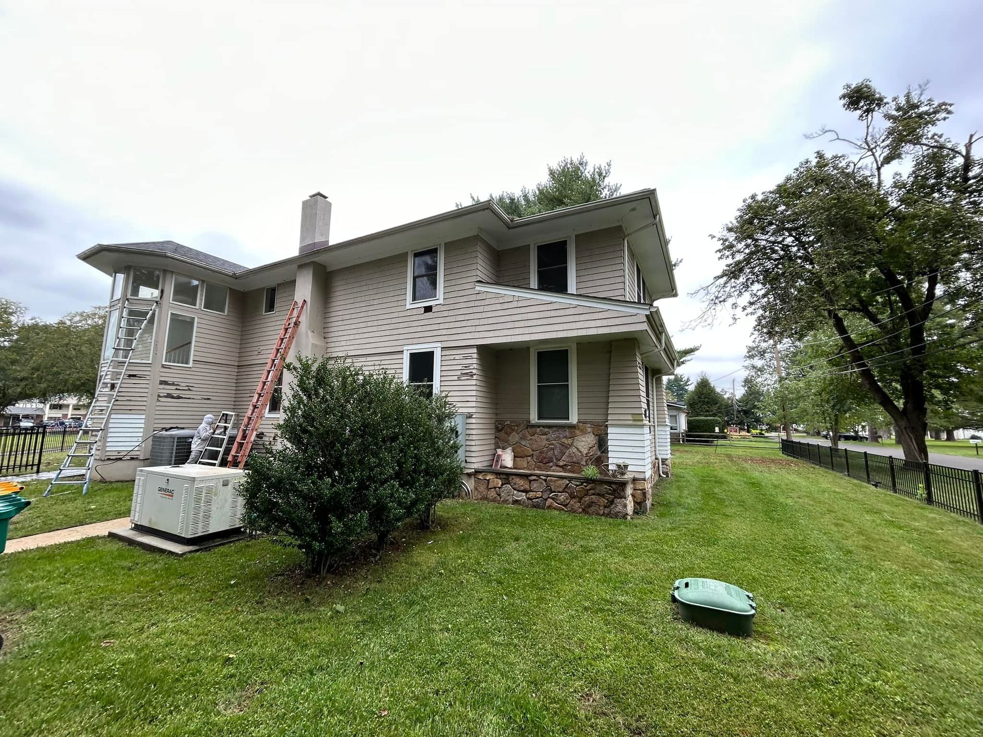 A house is being painted with a ladder in the backyard.