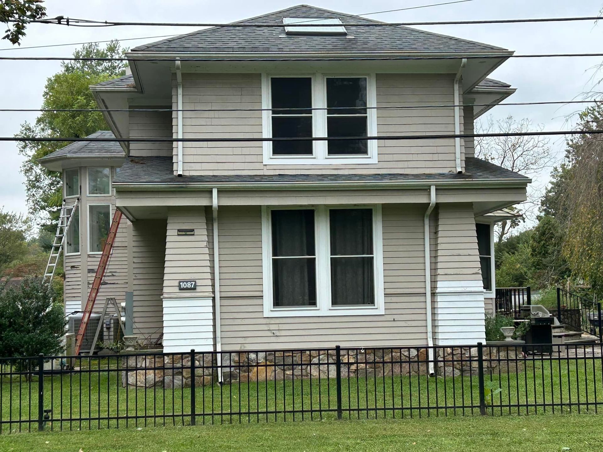 A house with a ladder in front of it and a fence around it.