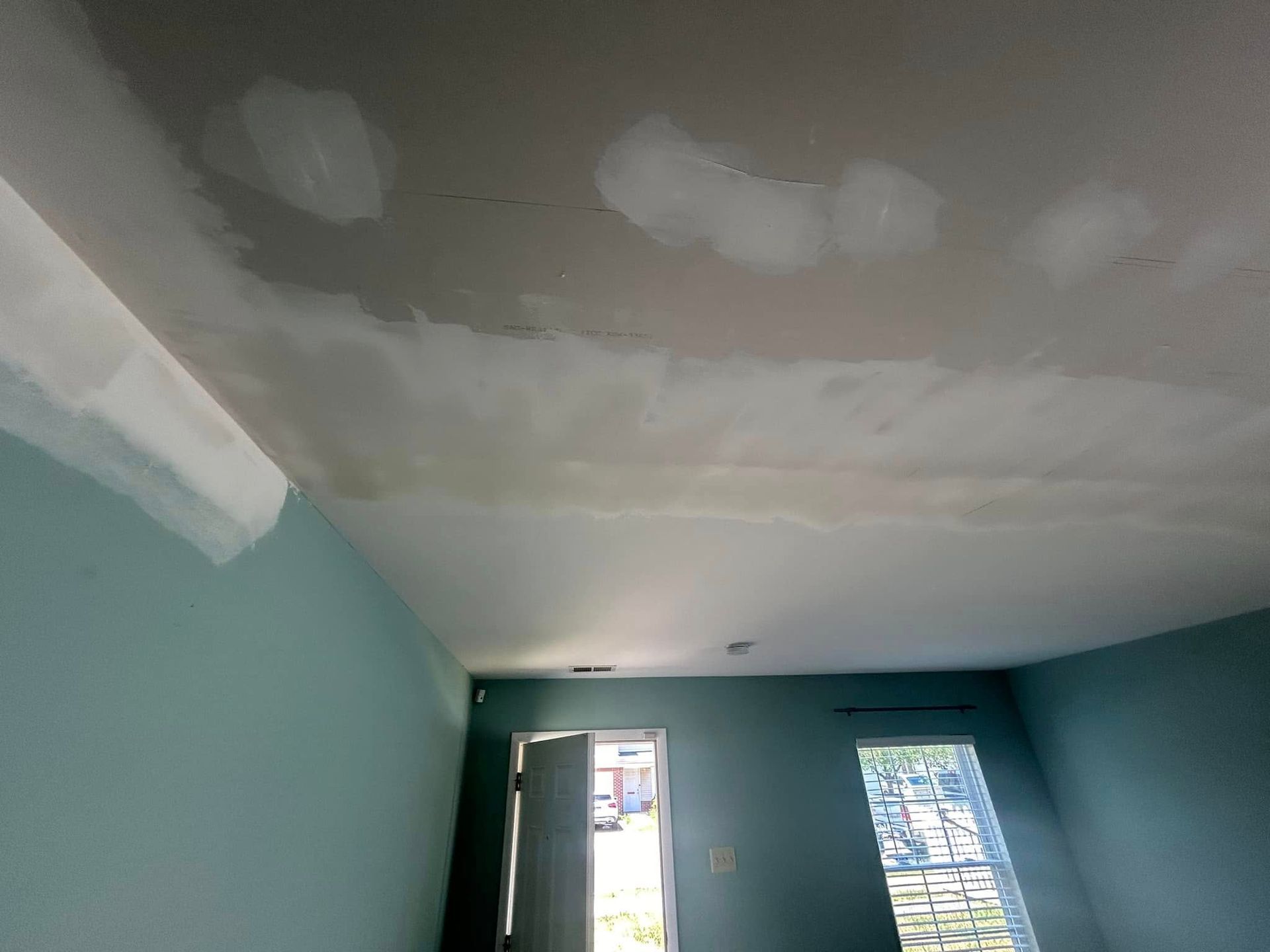 A room with blue walls and a white ceiling is being painted.