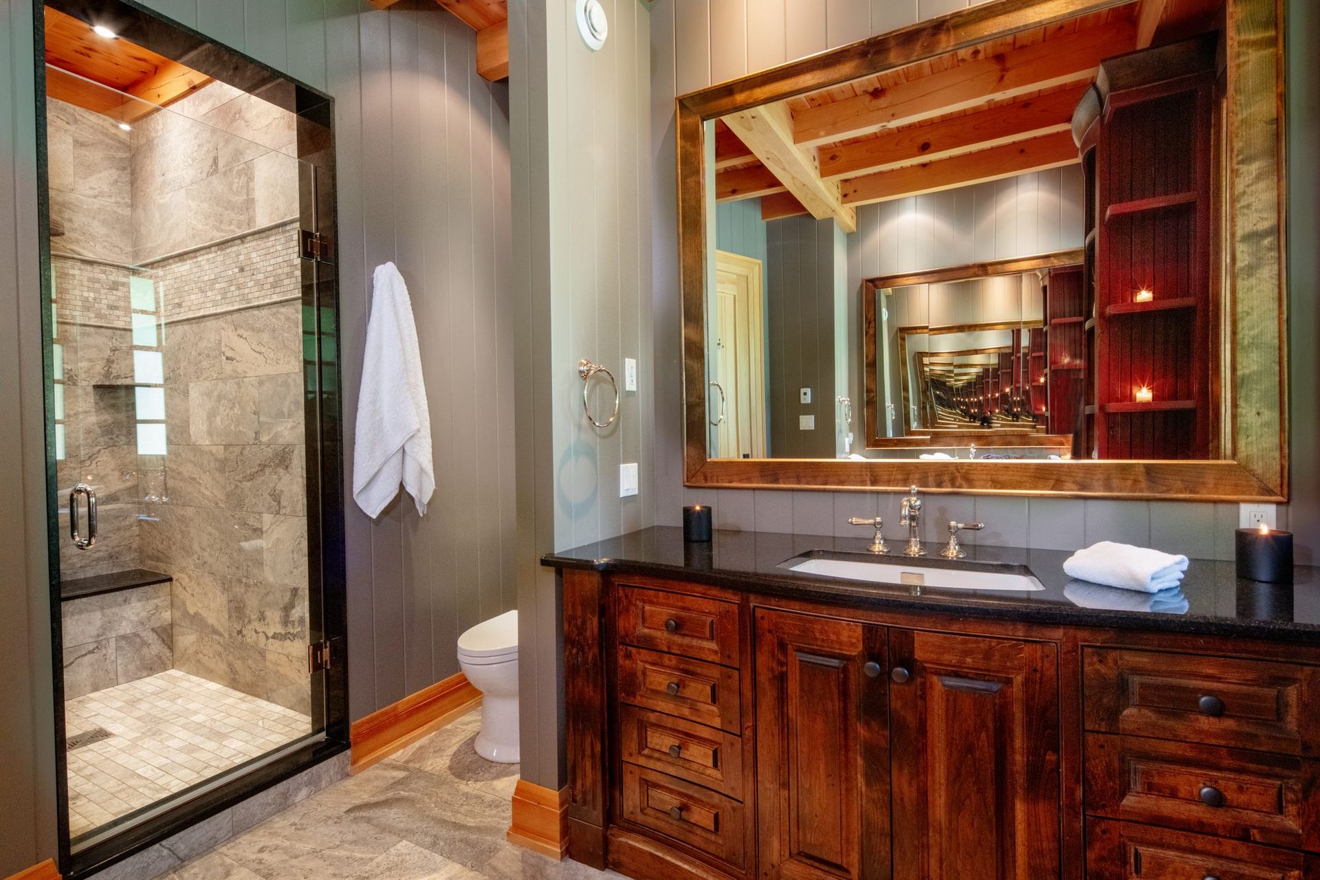 Luxury bathroom with walk-in stone shower, wooden vanity, and large mirror