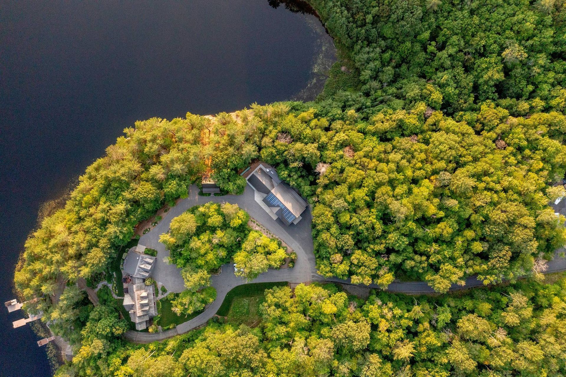 Aerial view of lakeside cabins surrounded by dense green forest