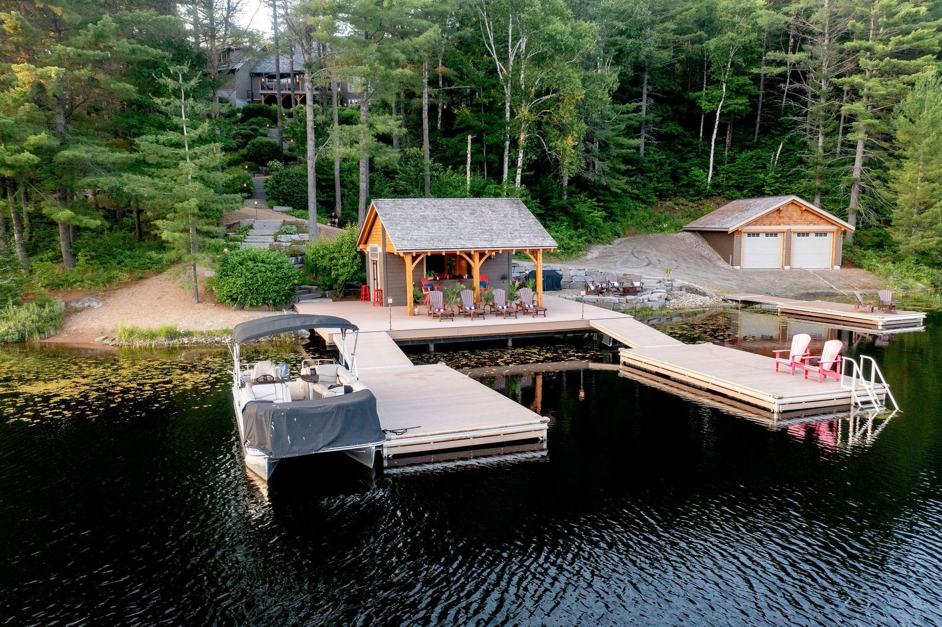 Wooden dock with small boathouse on a forested lake, with people standing near the pier