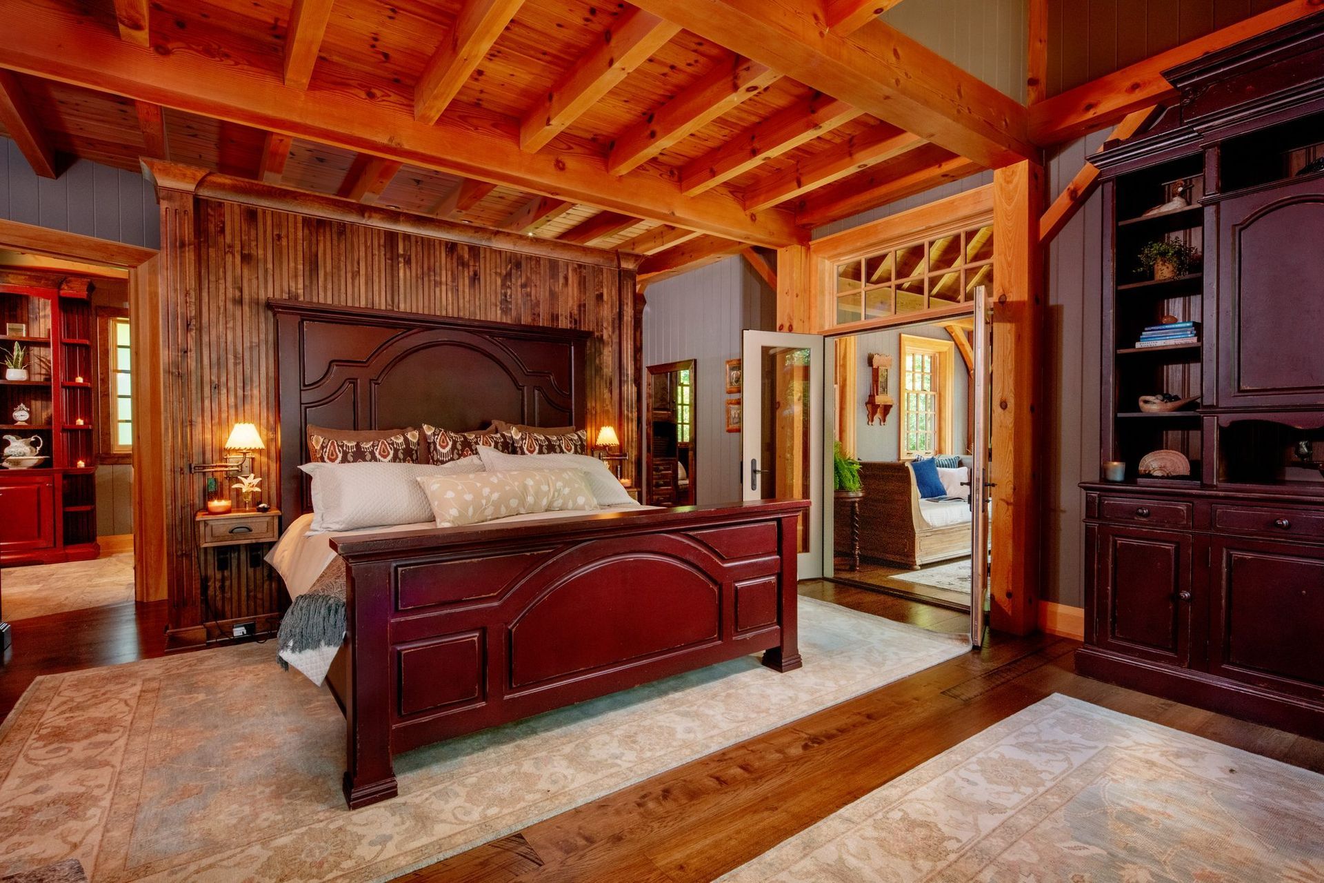 Wood-paneled bedroom with a carved wooden bed, exposed beams, and warm rustic décor