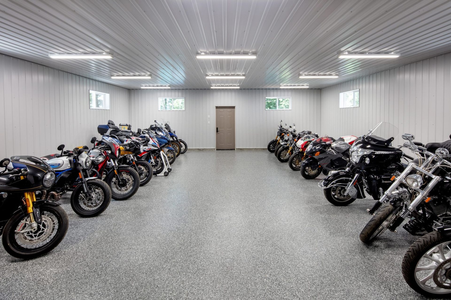 Motorcycles lined up on both sides of a bright indoor showroom with white walls and ceiling lights