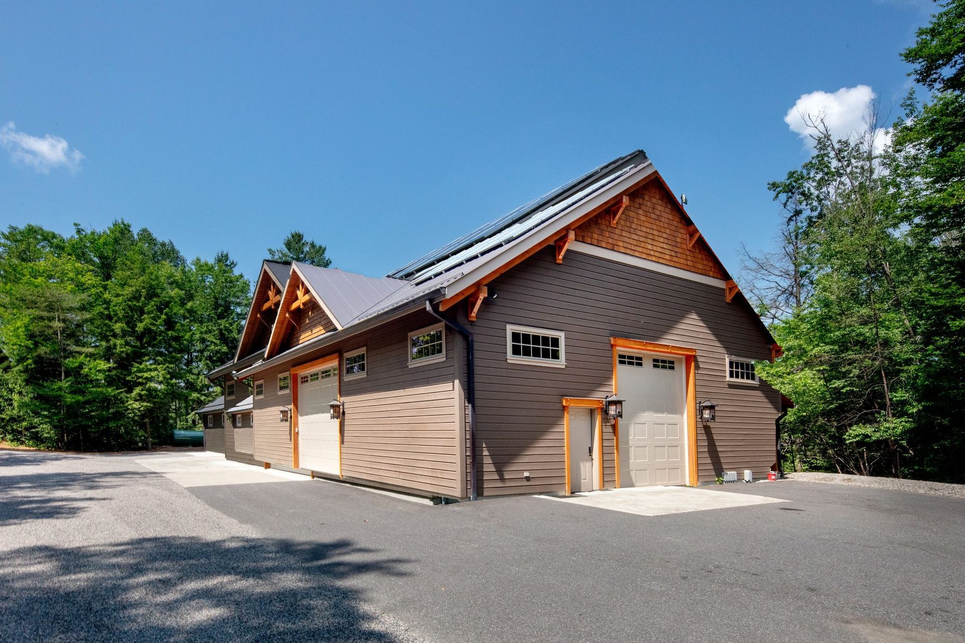 Brown cabin-style building with red-trimmed roofs, small windows, and a gravel lot under a blue sky