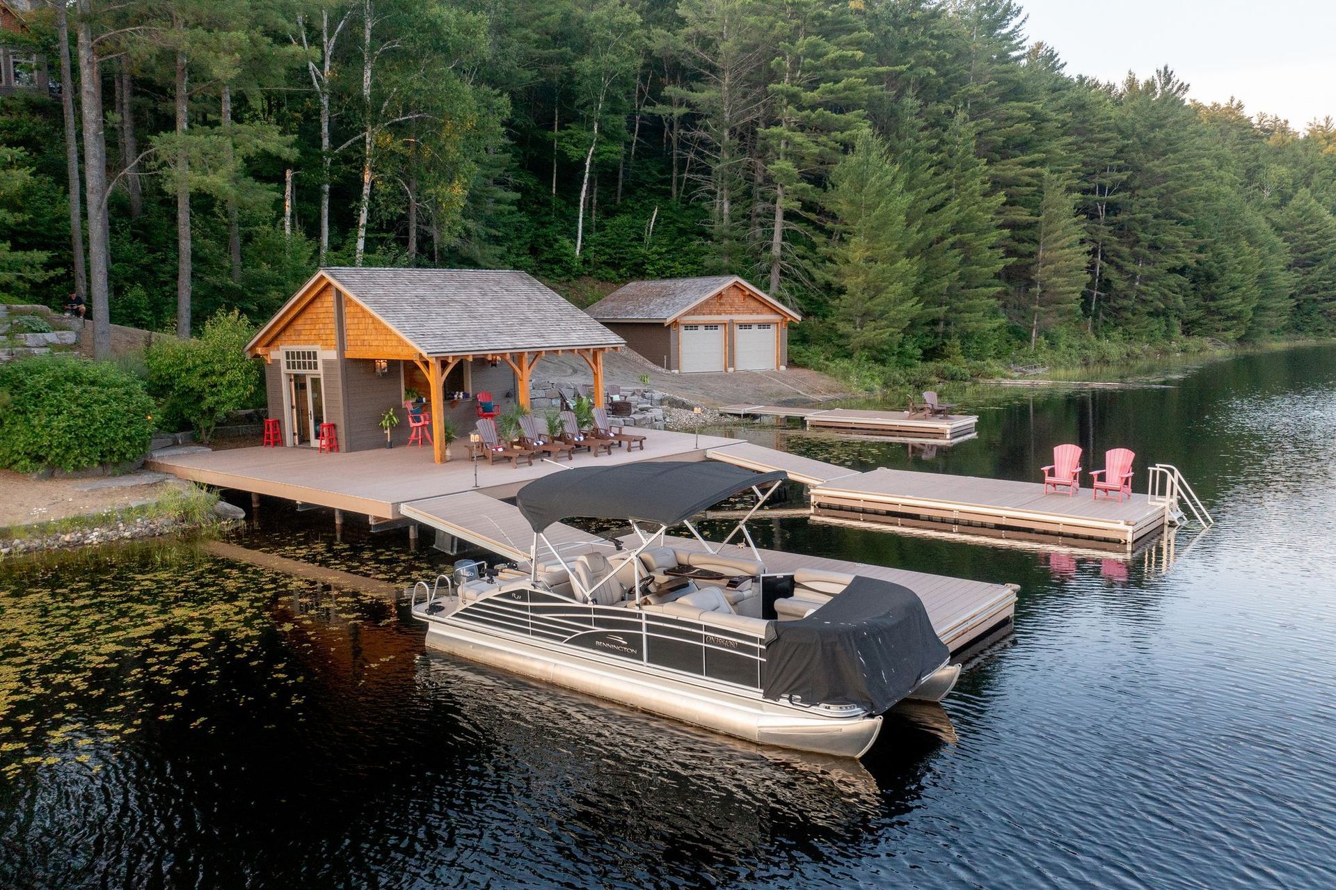 Lake dock with two covered boats beside a small orange boathouse in a forested cove