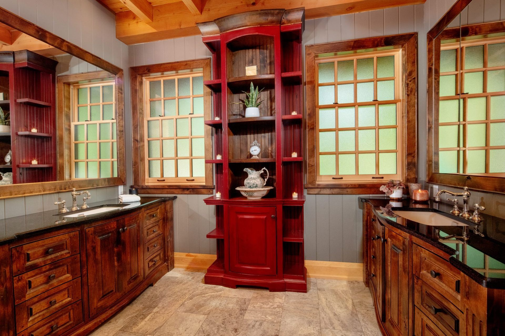 Red kitchen with wooden cabinets, black countertops, large windows, and a central red display shelf.