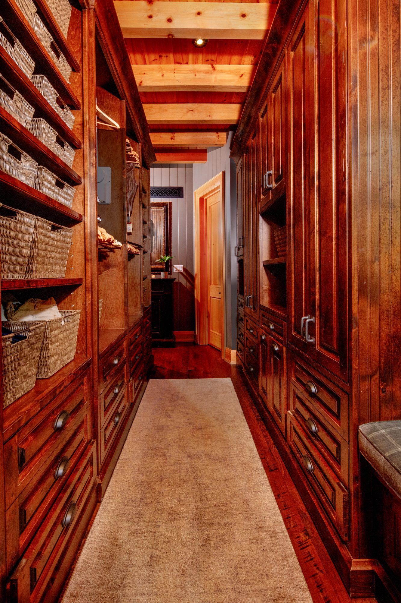 Narrow wood-paneled hallway with built-in shelves, cabinets, and a beige runner rug