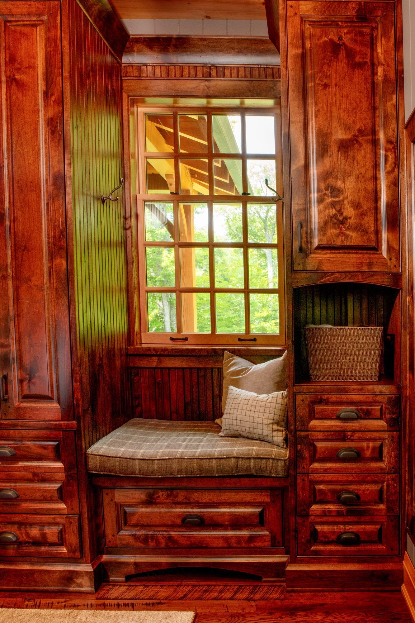 Cozy wooden nook with built-in bench, cushions, and a sunlit window