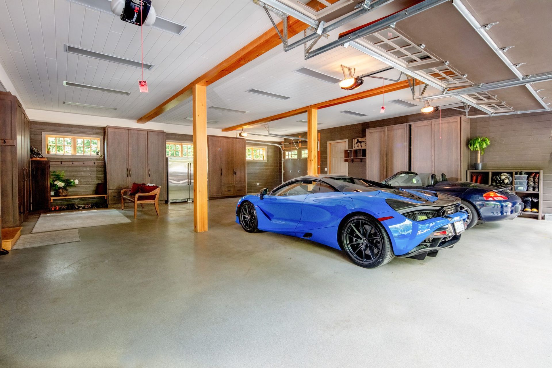 Modern garage interior with two blue sports cars parked on a polished concrete floor