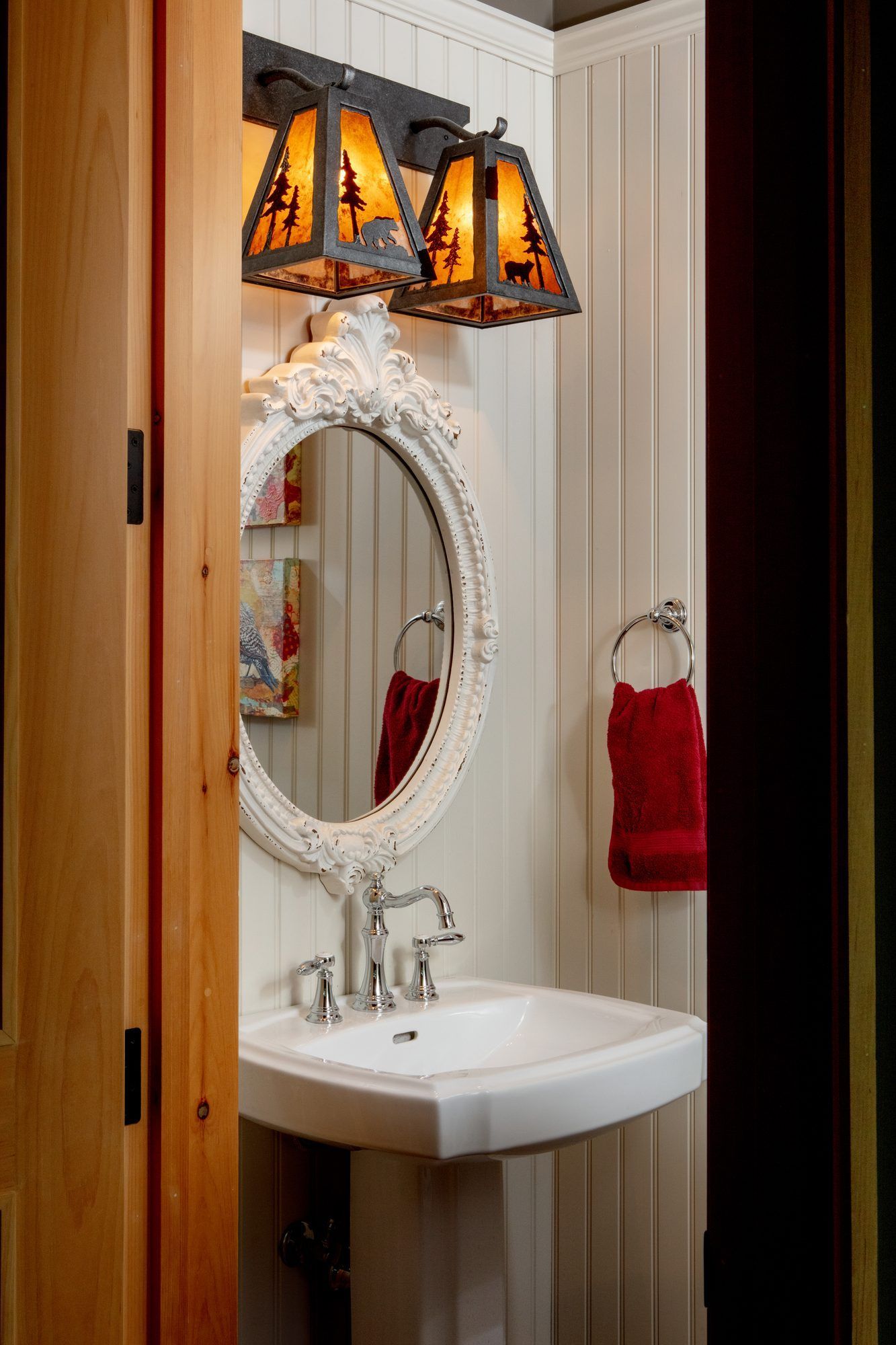 Small bathroom vanity with oval mirror, white sink, and orange-black pendant light.