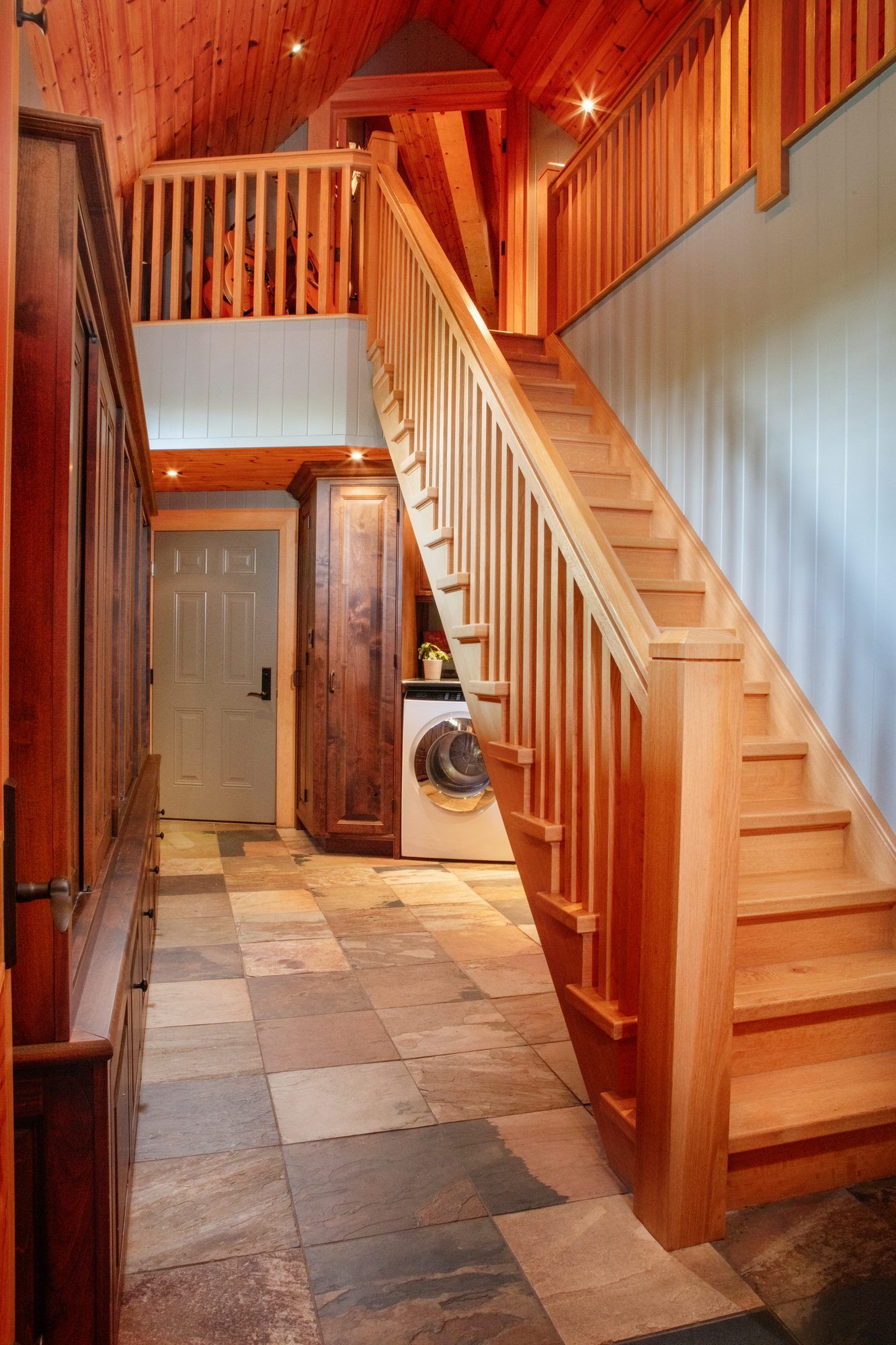 Wooden staircase in a cozy hallway with checkered tile floor and warm wood-paneled walls