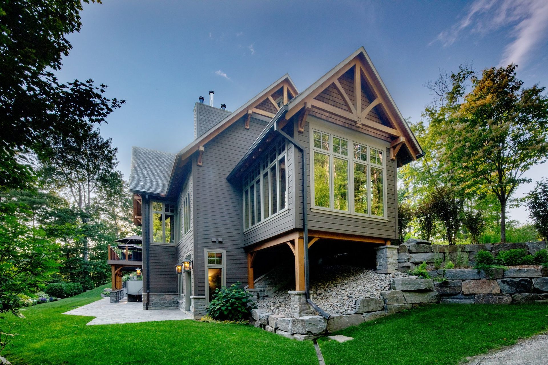 Modern gray house with gabled roof and large windows in a green wooded yard