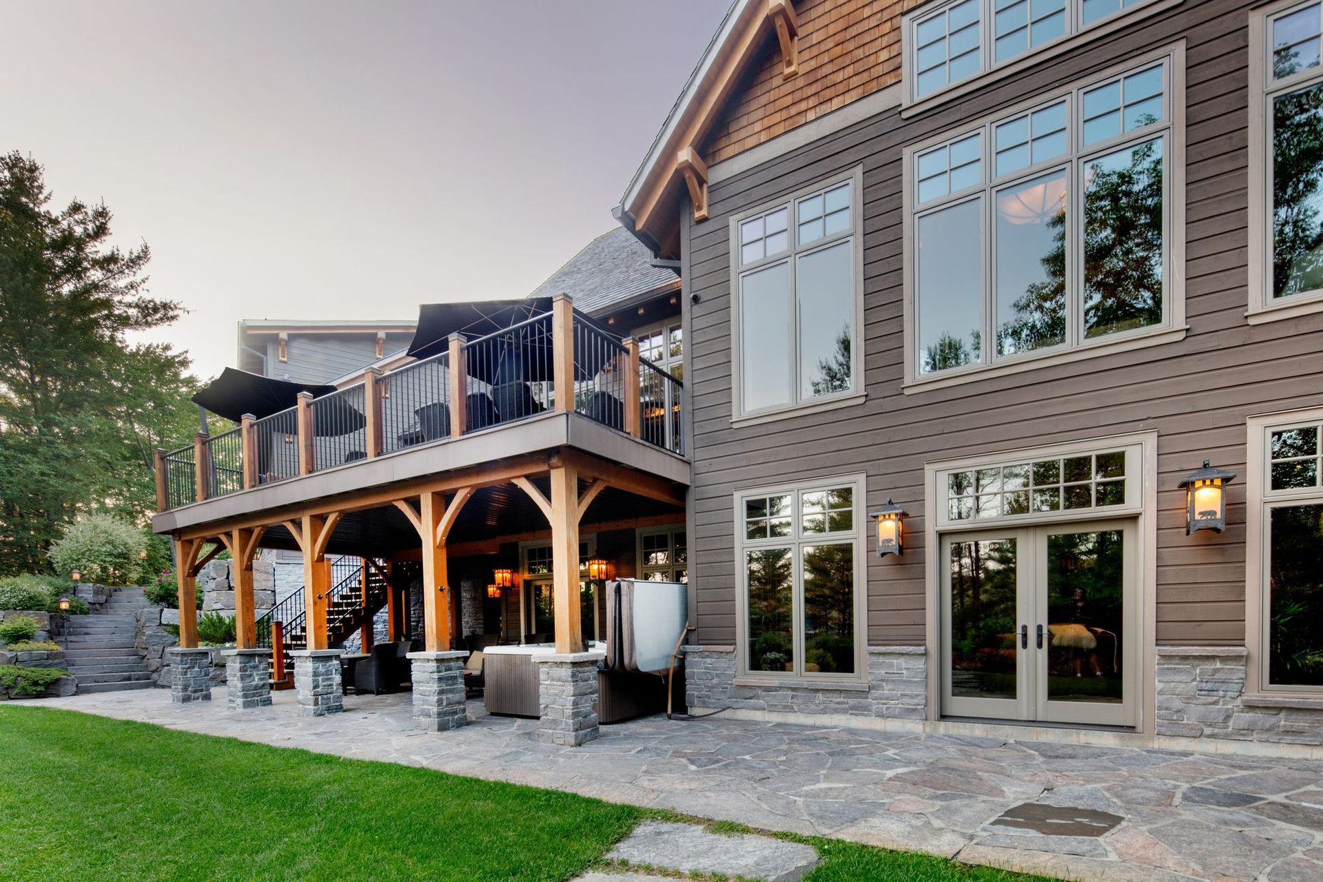 Brick house with a covered porch, stone patio, and landscaped lawn at dusk