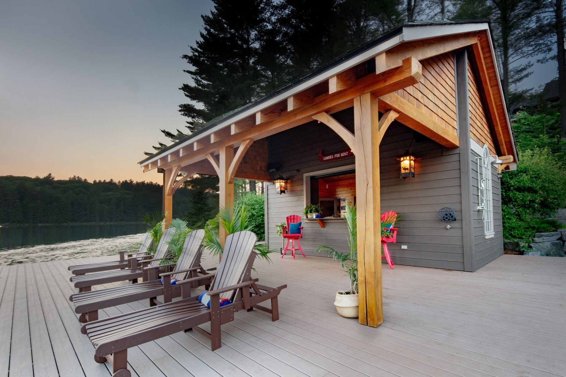Lakeside cabin porch with lounge chairs and colorful kayak at sunset
