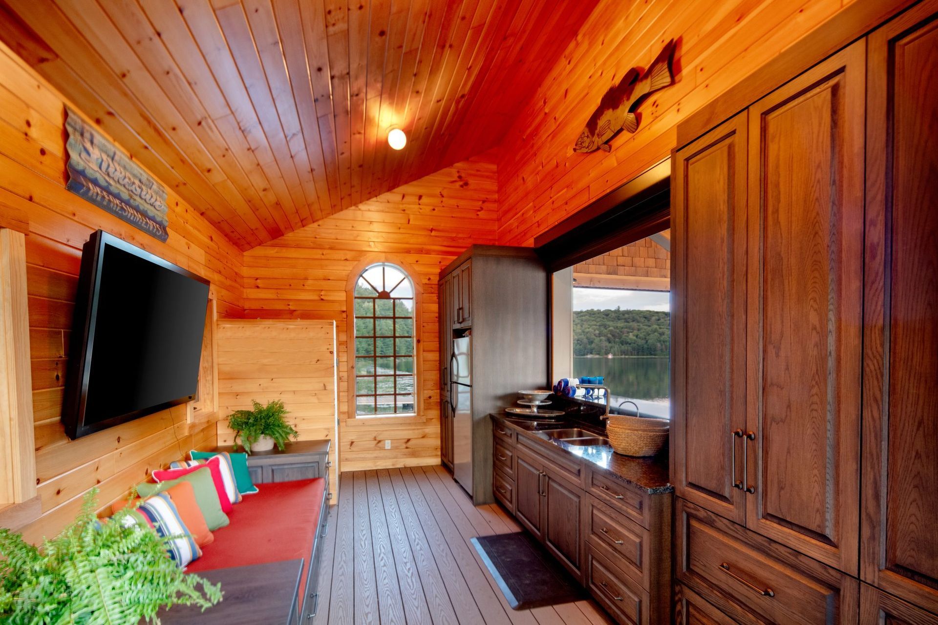 Cozy wood-paneled cabin room with TV, sofa, built-in cabinets, and a door to the outside
