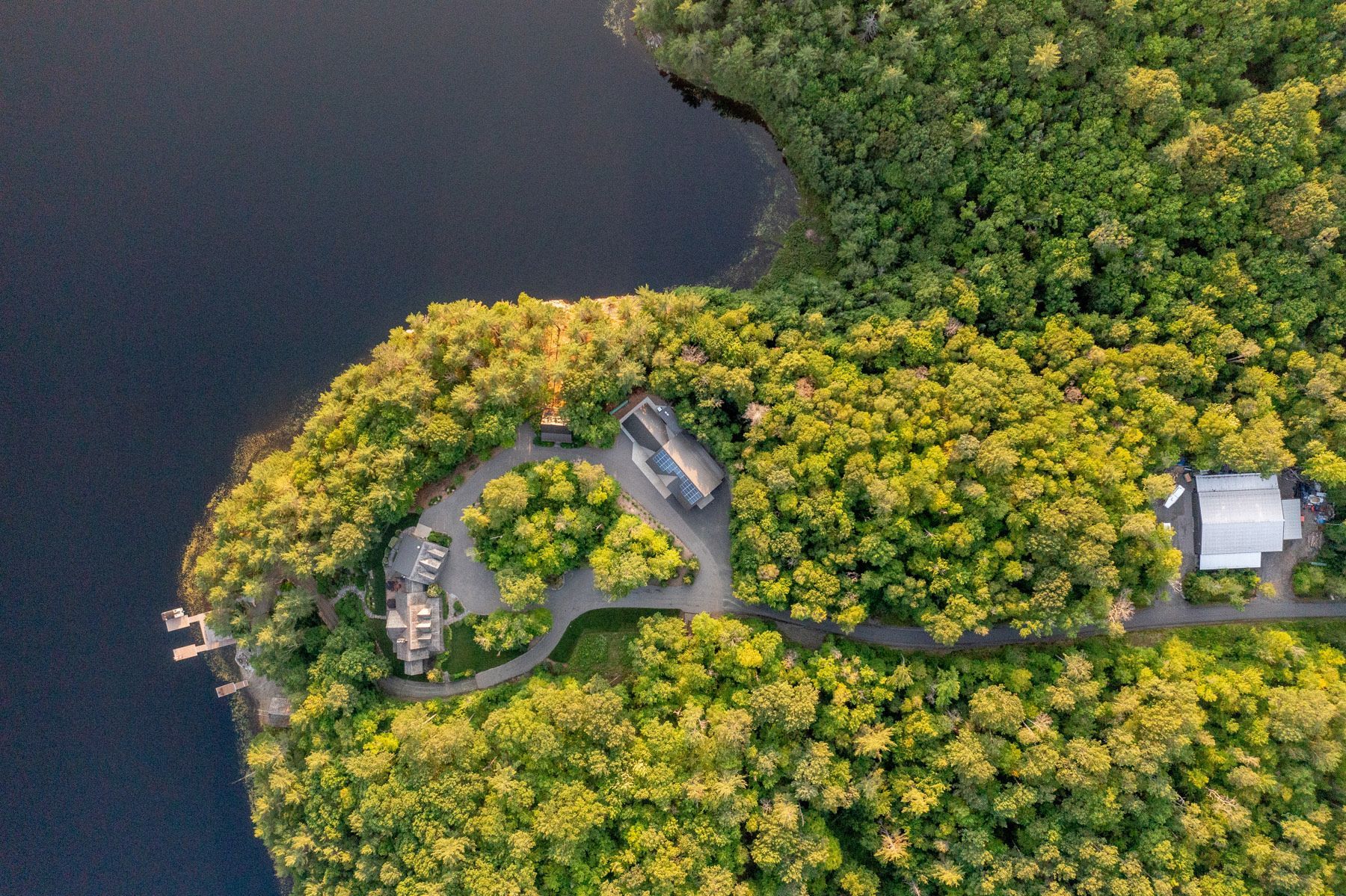An aerial view of a lake surrounded by trees and a road.