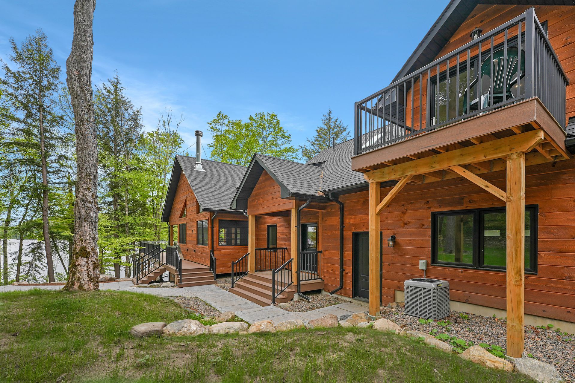 Wooden cabin with stone patio and balcony in a wooded lakeside setting