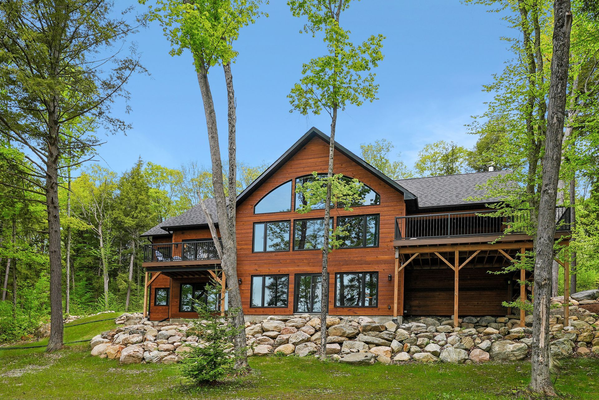 Modern wooden cabin with large windows in a green forest setting