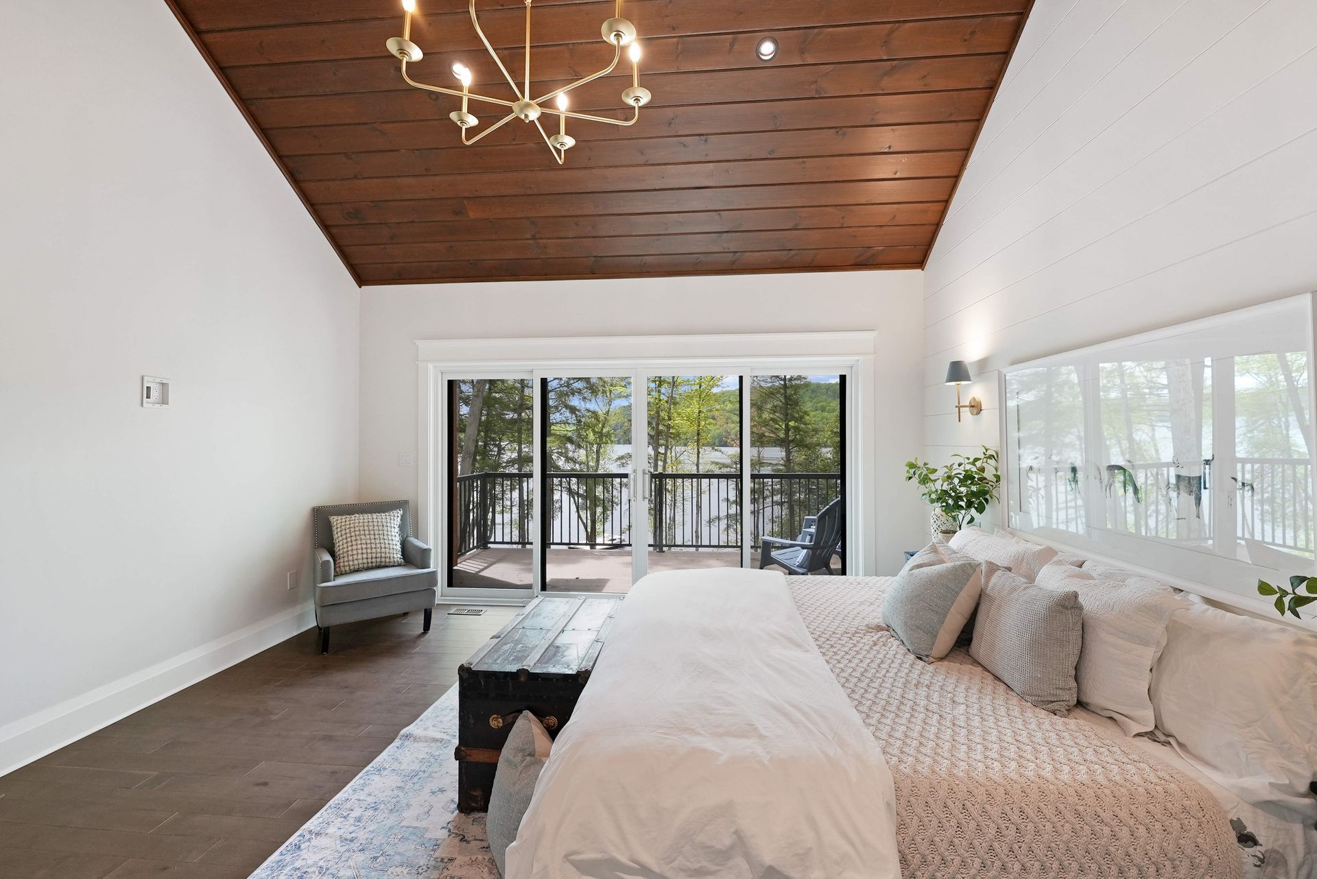 Bright bedroom with a wooden ceiling, large windows, and a bed facing glass doors to a deck.