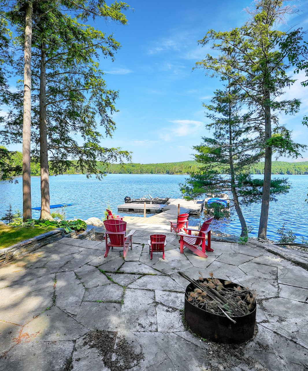 A deck with wicker furniture and umbrellas overlooking a lake
