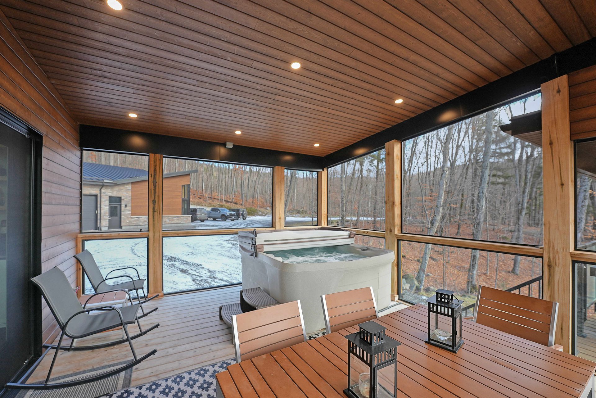 Covered patio with wooden ceiling, seating, lanterns, and a snowy backyard view