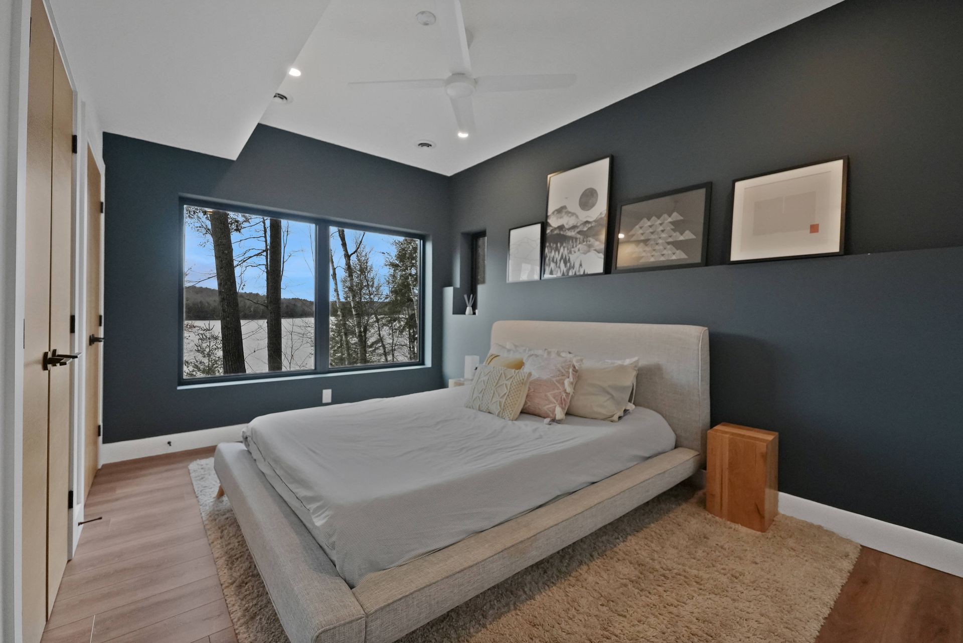 Modern bedroom with gray walls, window view, platform bed, and minimalist wall art