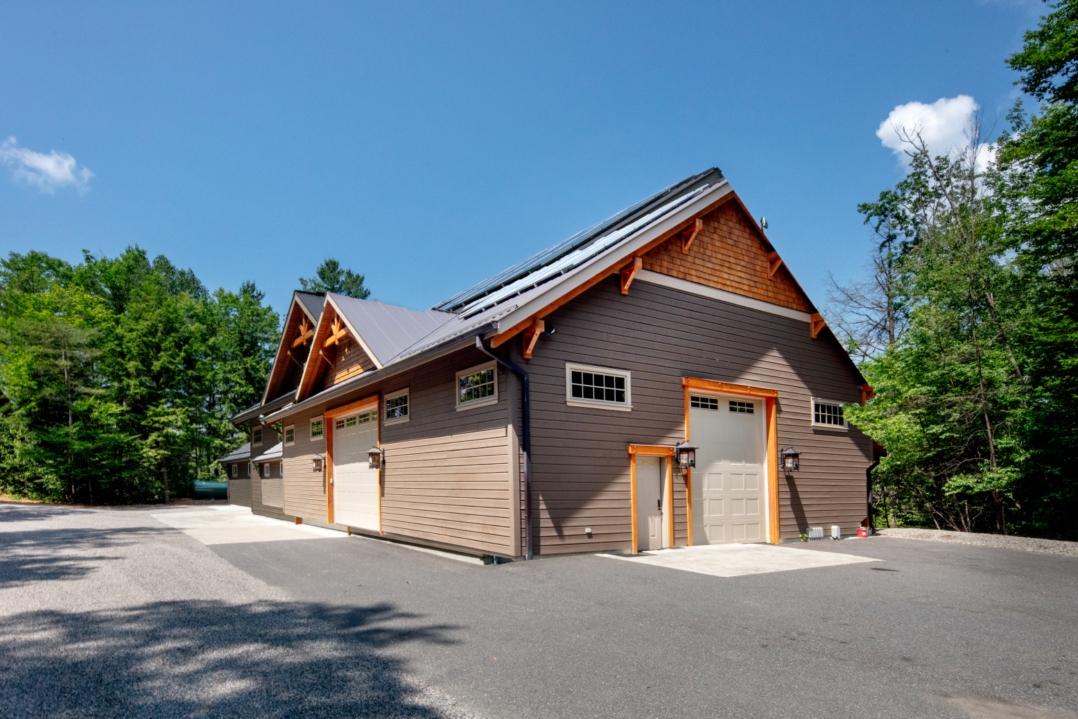 A large brown garage with a wooden roof is surrounded by trees.