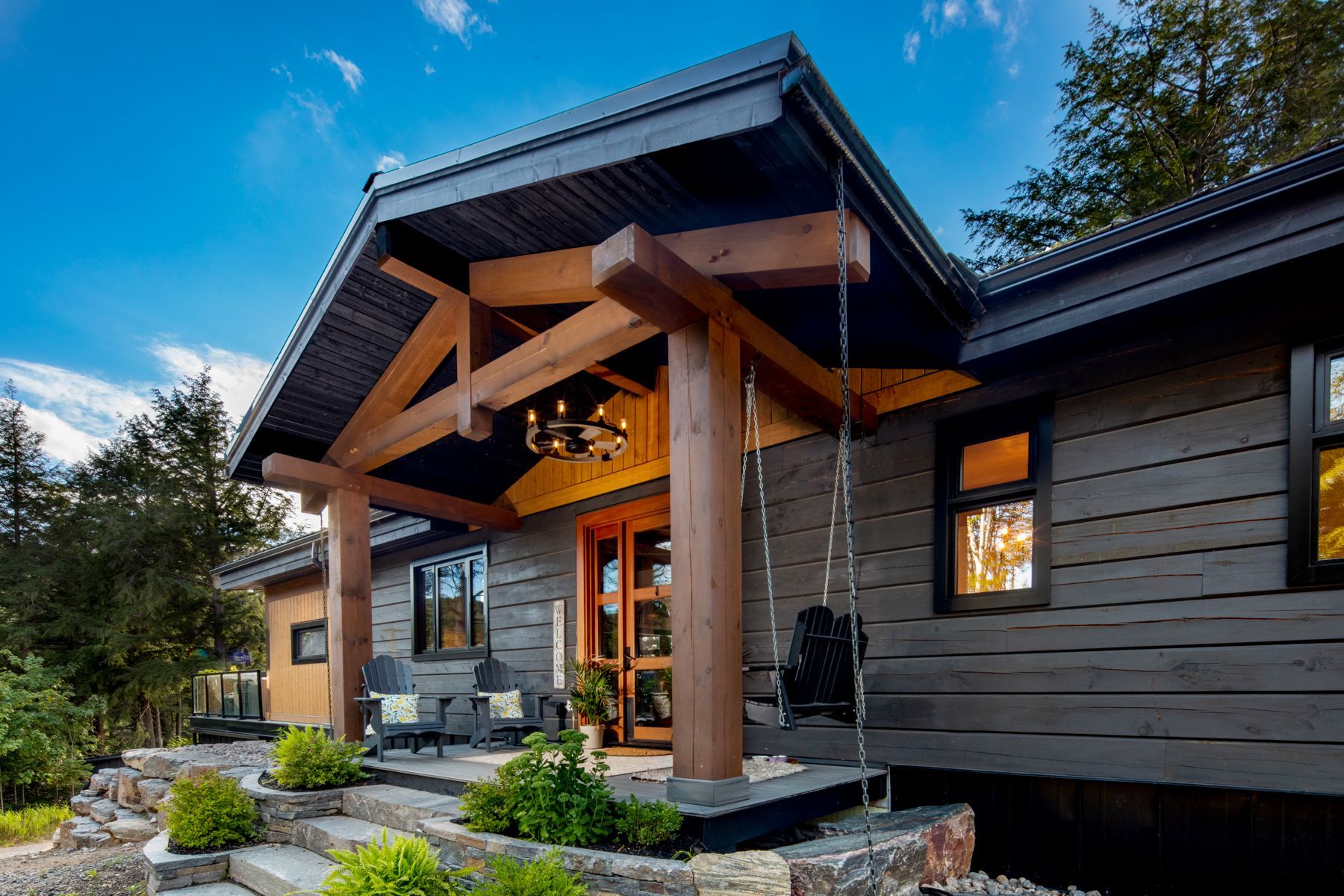 A small house with a porch in the middle of a forest.