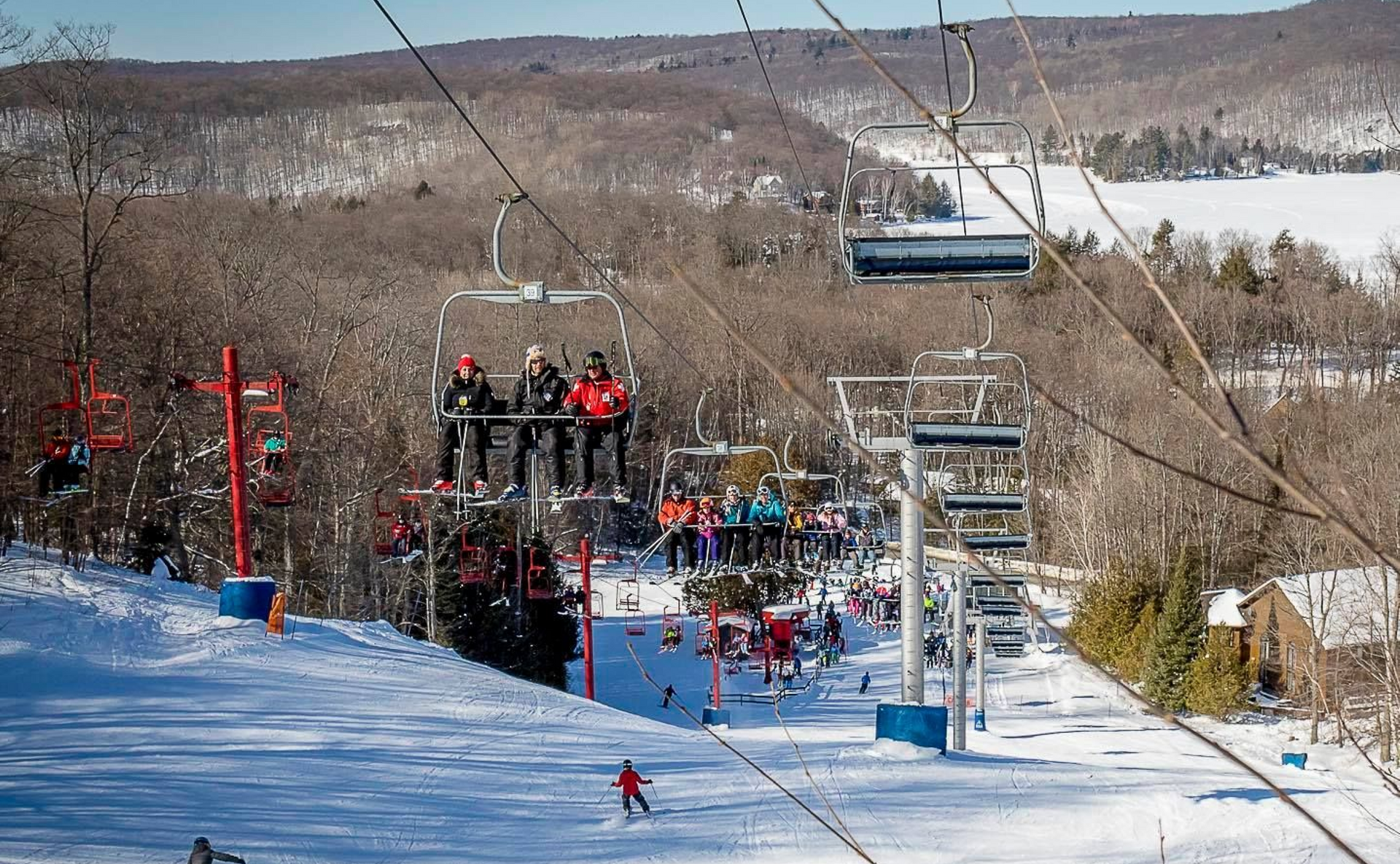 A group of people are riding a ski lift down a snow covered slope.