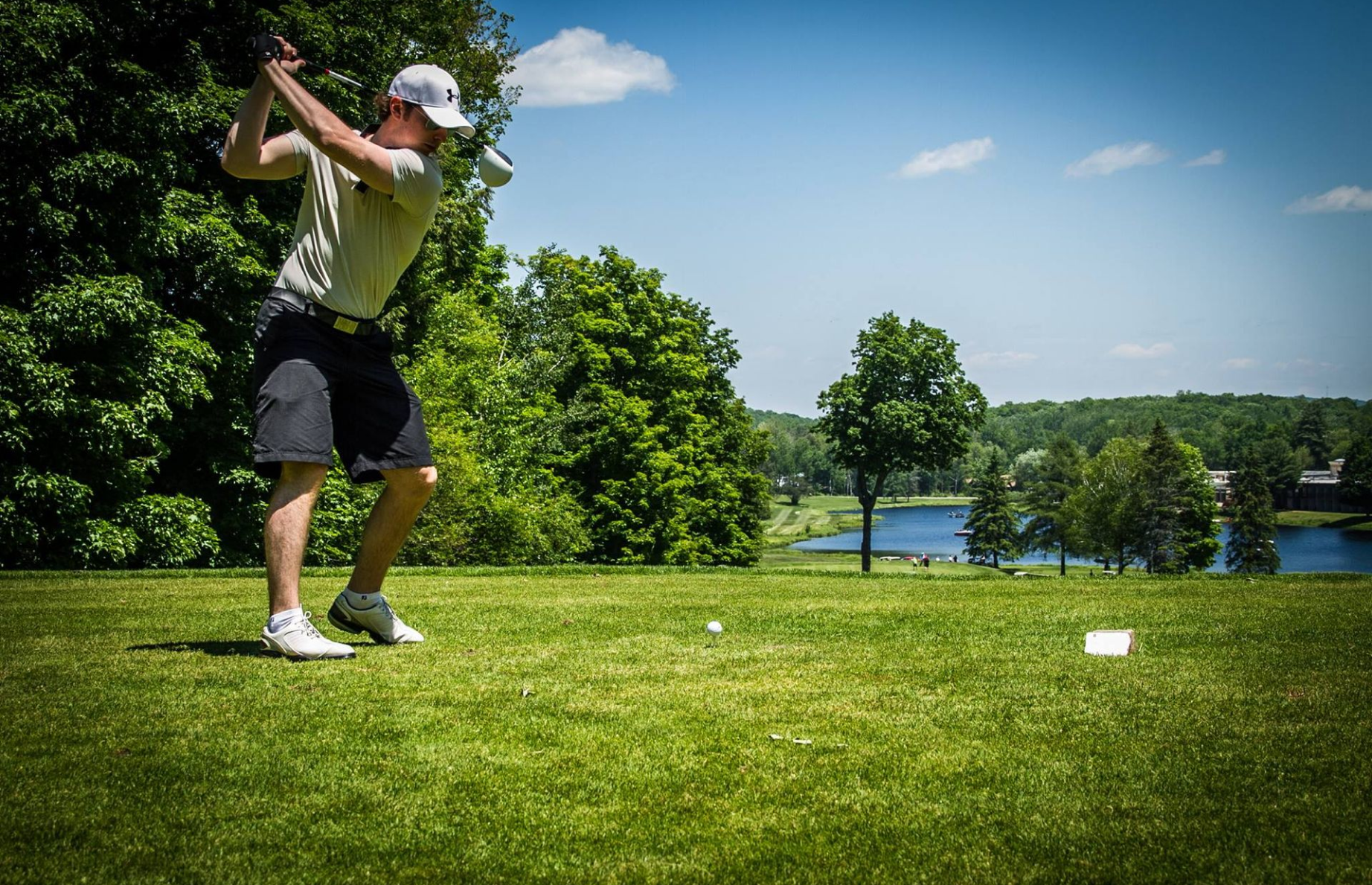 A man is swinging a golf club on a golf course.