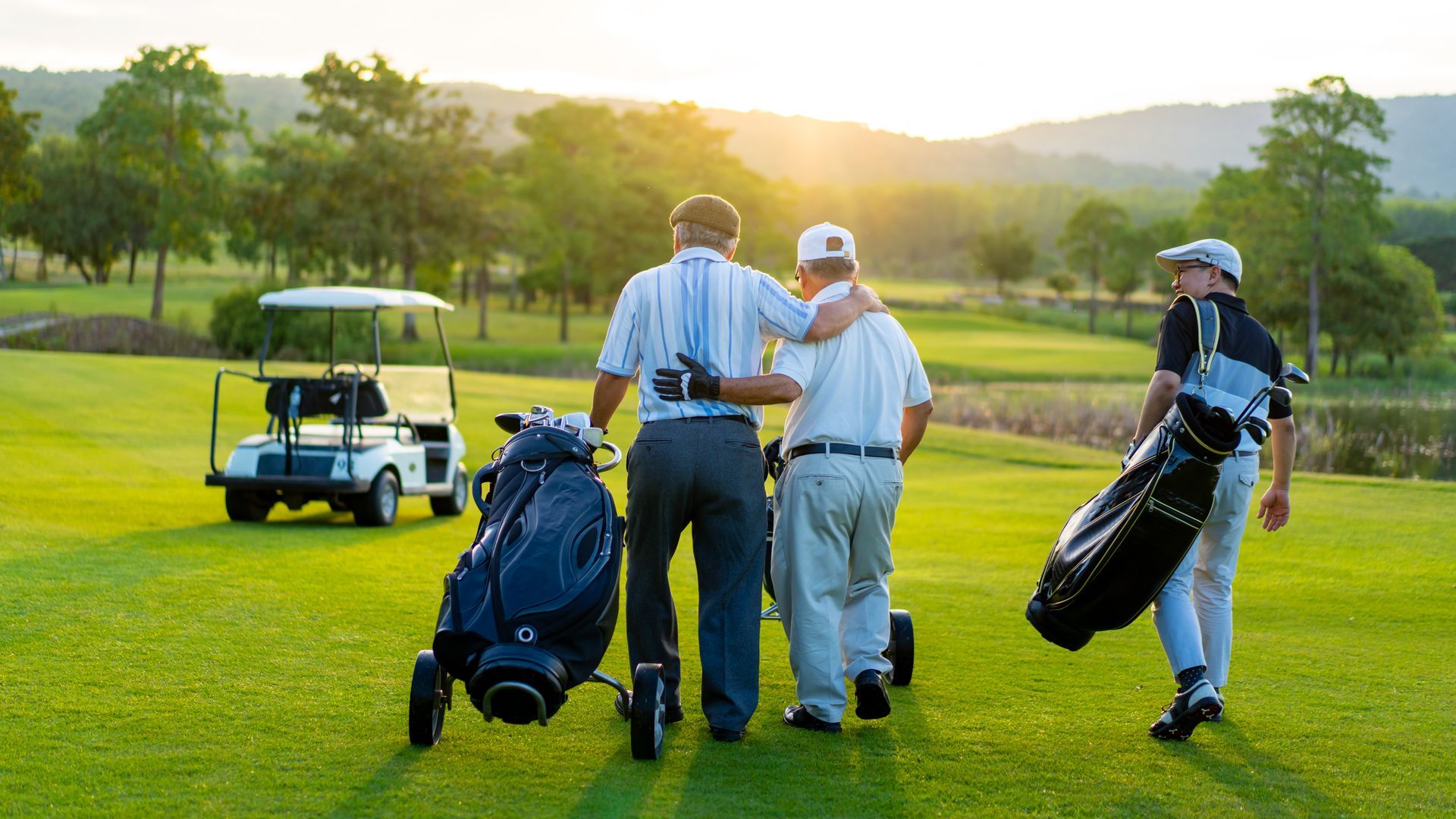 Three men are walking on a golf course with golf bags.
