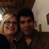A man and a woman are posing for a picture together . the woman is wearing glasses.