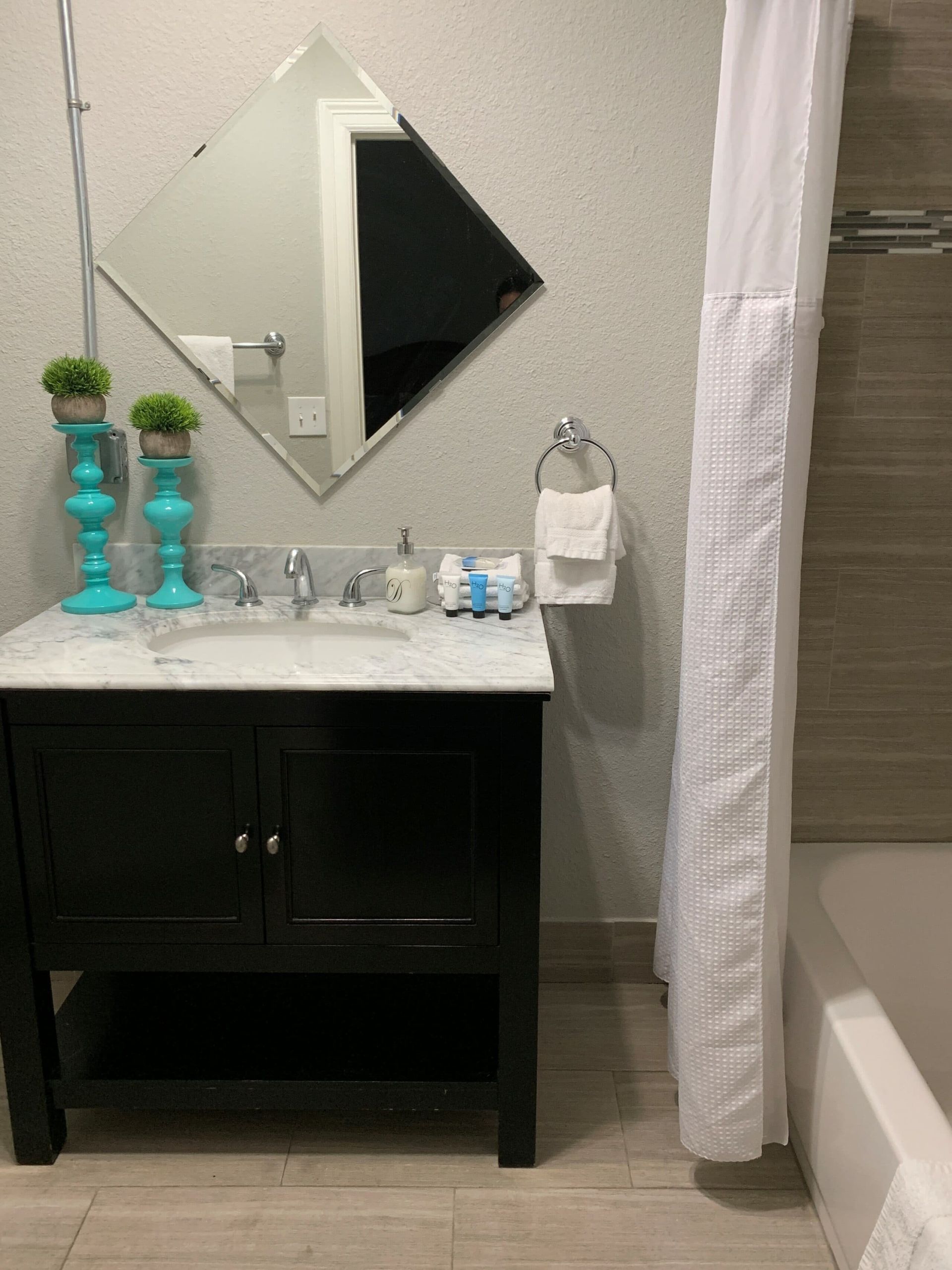 A bathroom with a sink , mirror and shower curtain.