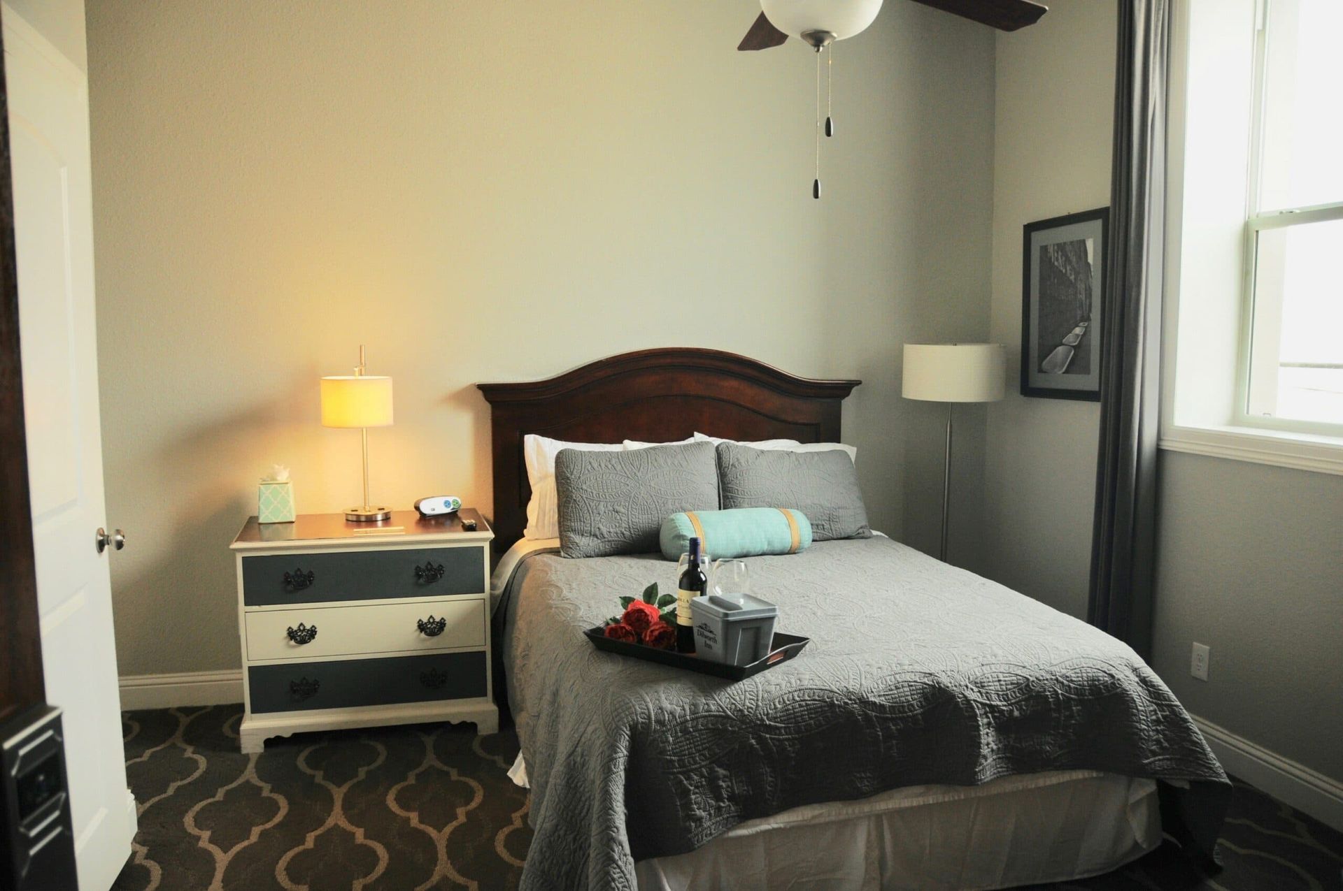 A bedroom with a bed , nightstand , lamp and window