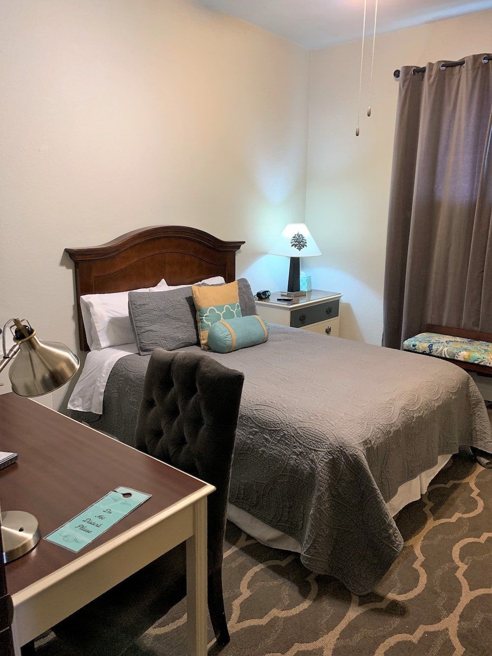 A bedroom with a bed , desk , chair and window.