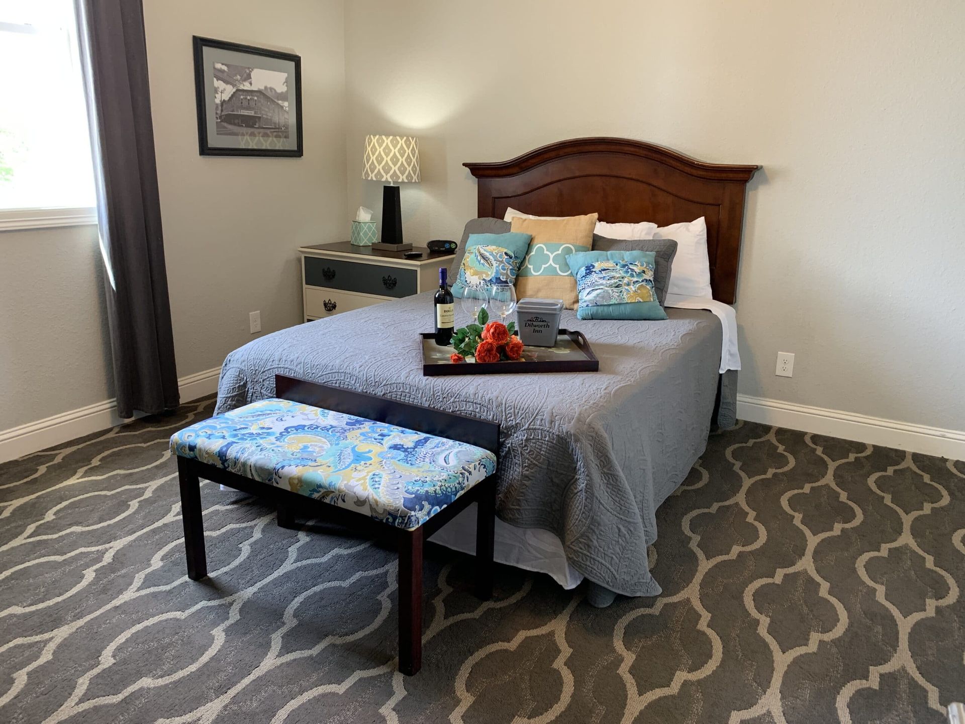 A bedroom with a bed and a bench with a tray on it.