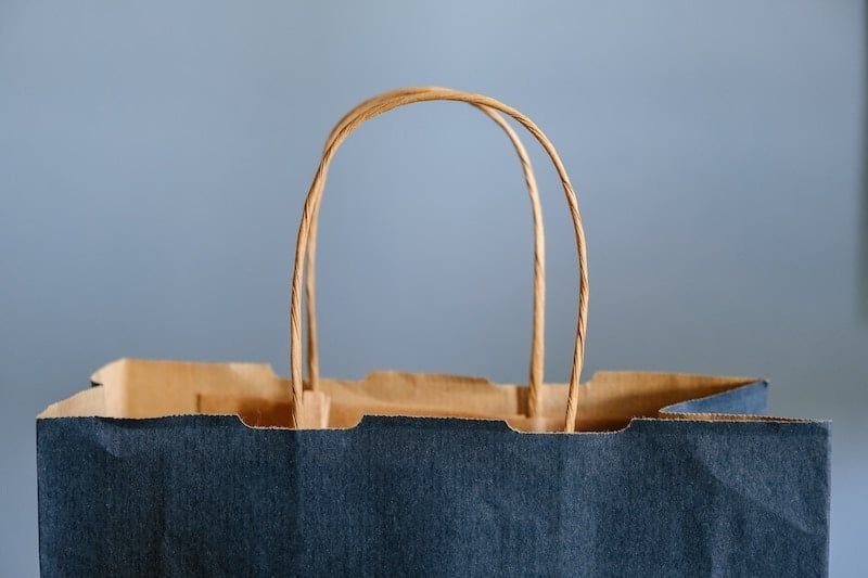A black paper bag with a brown handle is sitting on a table.