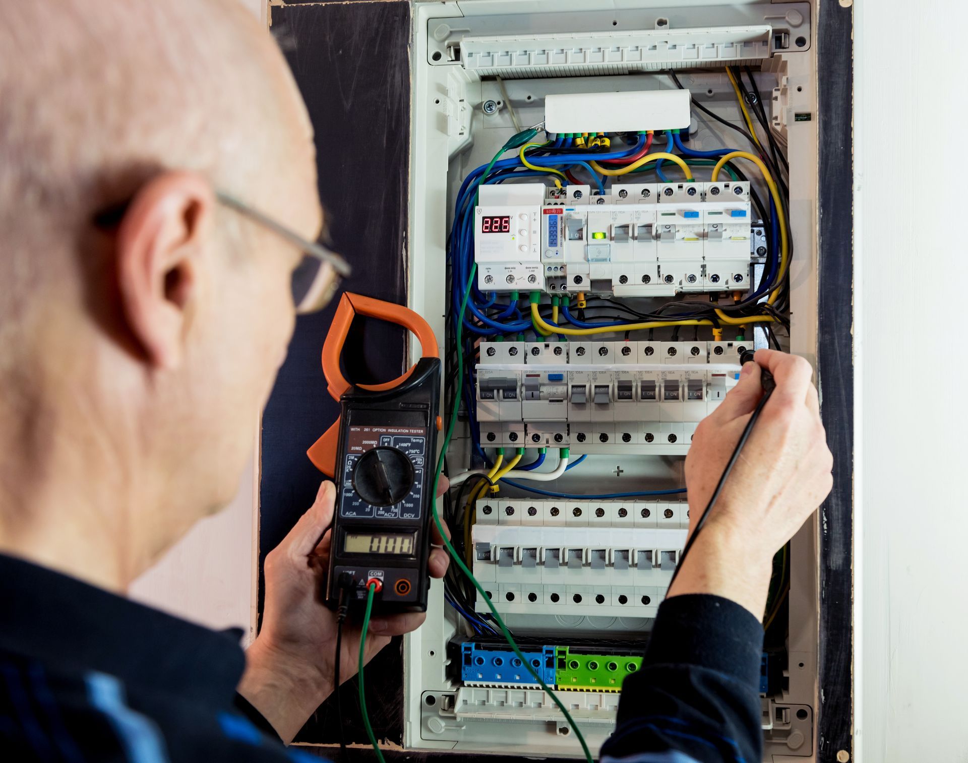 Electrician testing circuits with a multimeter inside an electrical panel. Electrician testing circuits with a multimeter inside an electrical panel.